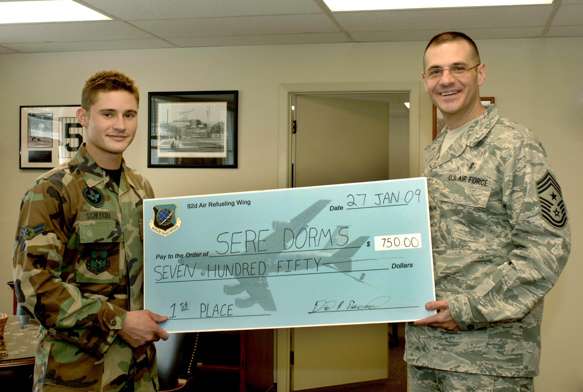 FAIRCHILD AIR FORCE BASE, Wash. – Airman 1st Class Lorin Schlecht, 22nd Training Squadron, accepts the Dorm of the Quarter Award, a check for $750, from Chief Master Sgt. David Nordel, 92nd Air Refueling Wing command chief, on behalf of the Survival, Evasion, Resistance and Escape dormitory here Jan 27. (U.S. Air Force photo / Airman 1st Class Darlene West)
