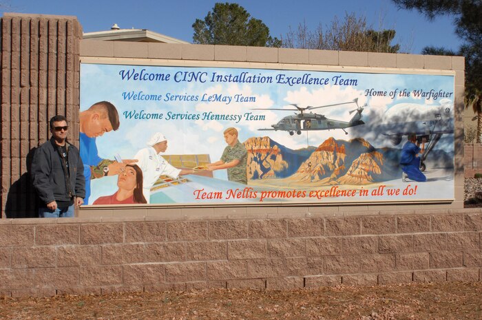 Mr. Marty Purdy, a member of the 99th Civil Engineer Squadron's structural shop, poses with a new sign that he designed and painted as part of Nellis' entrance Jan. 27. (U. S. Air Force photo by Staff Sgt. Taylor Worley)