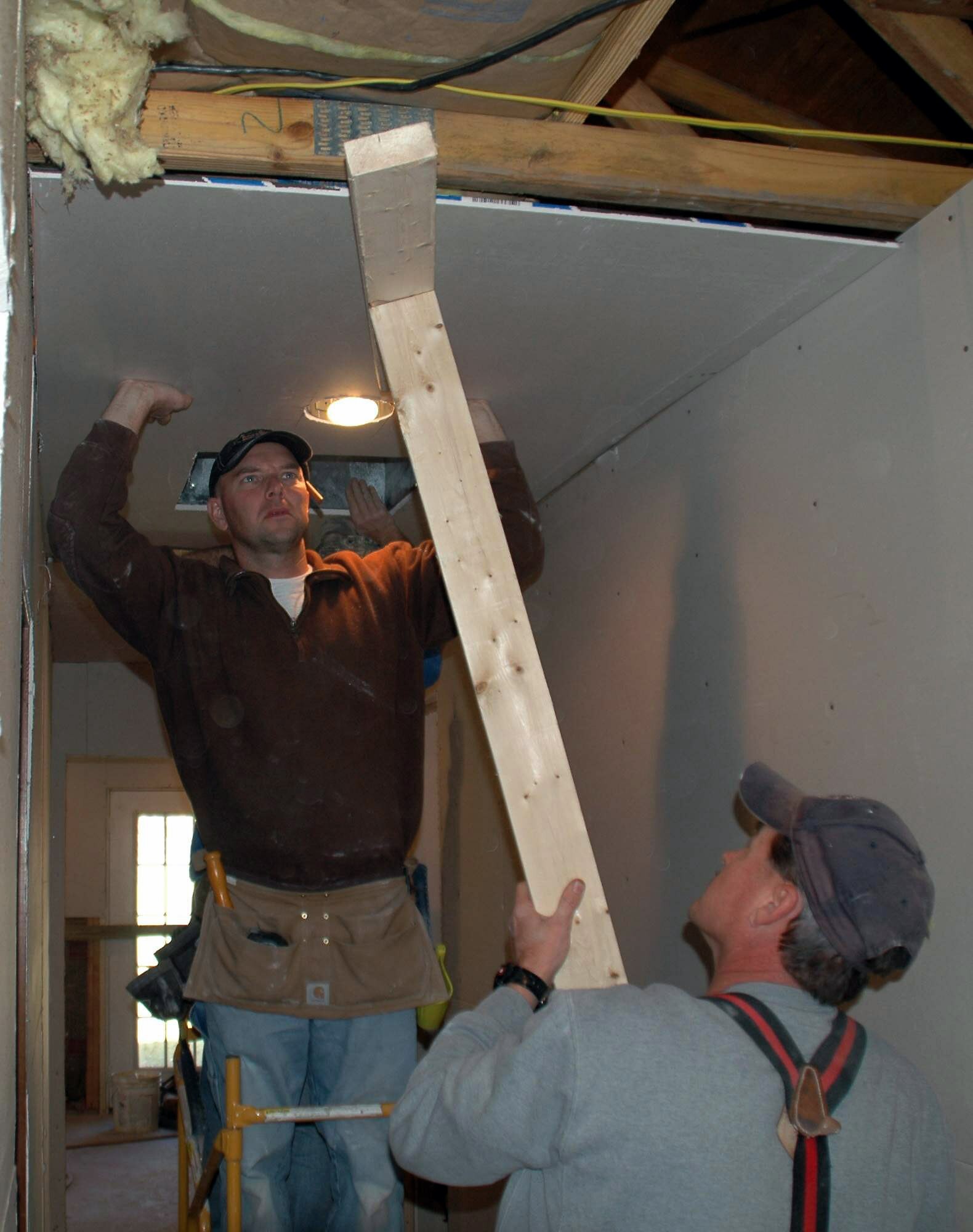 Master Sgts. Shawn Delp and Peter Shovey install sheetrock in a newly widened hall at the home of Master Sgt. Don Eagle in December in Charleston, S.C. Members of Charleston Air Force Base worked on Sergeant Eagle's house since November to make it handicap accessible. Sergeant Eagle was struck by a motorist as he drove his motorcycle home in April 2008, and he is currently a paraplegic. Sergeants Delp and Shovey are assigned to the 300th Airlift Squadron. (U.S. Air Force photo/Capt. Wayne Capps) 
