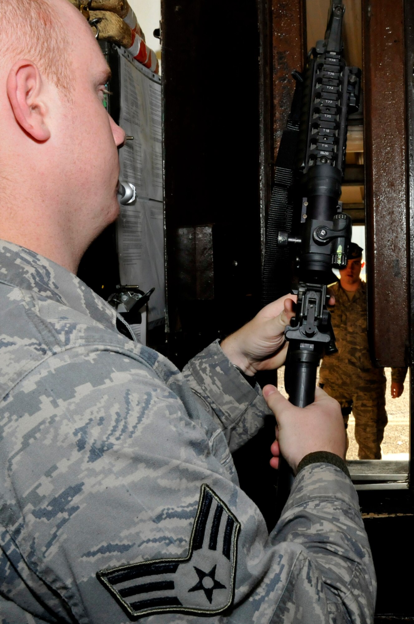 Senior Airman Jeremy Kelso, 48th Security Forces Squadron armors, looks over an M4A1 Assault Rifle one last time before instructing Senior Airman Craig Sams, 48th Security Forces Squadron to the window to receive his weapon Jan. 27 at RAF Lakenheath, England. The Security Forces Armory is manned 24 hours a day, seven days week. (U.S. Air Force photo by Airman 1st Class Perry Aston)