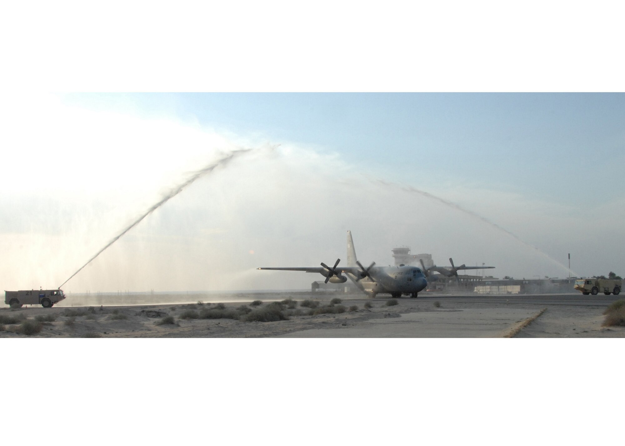 SOUTHWEST ASIA -- A C-130 passes through two fire trucks, hosing it down with water, after completing its final flight at an air base in Southwest Asia, Jan. 28.  Once a C-130 reaches 38,000 hours it recieves flight limitations and is used for ground training until 45,000 hours, after which it is sent to the boneyard at Davis-Monthan AFB, Ariz.  (U.S. Air Force photo/Senior Airman Courtney Richardson)