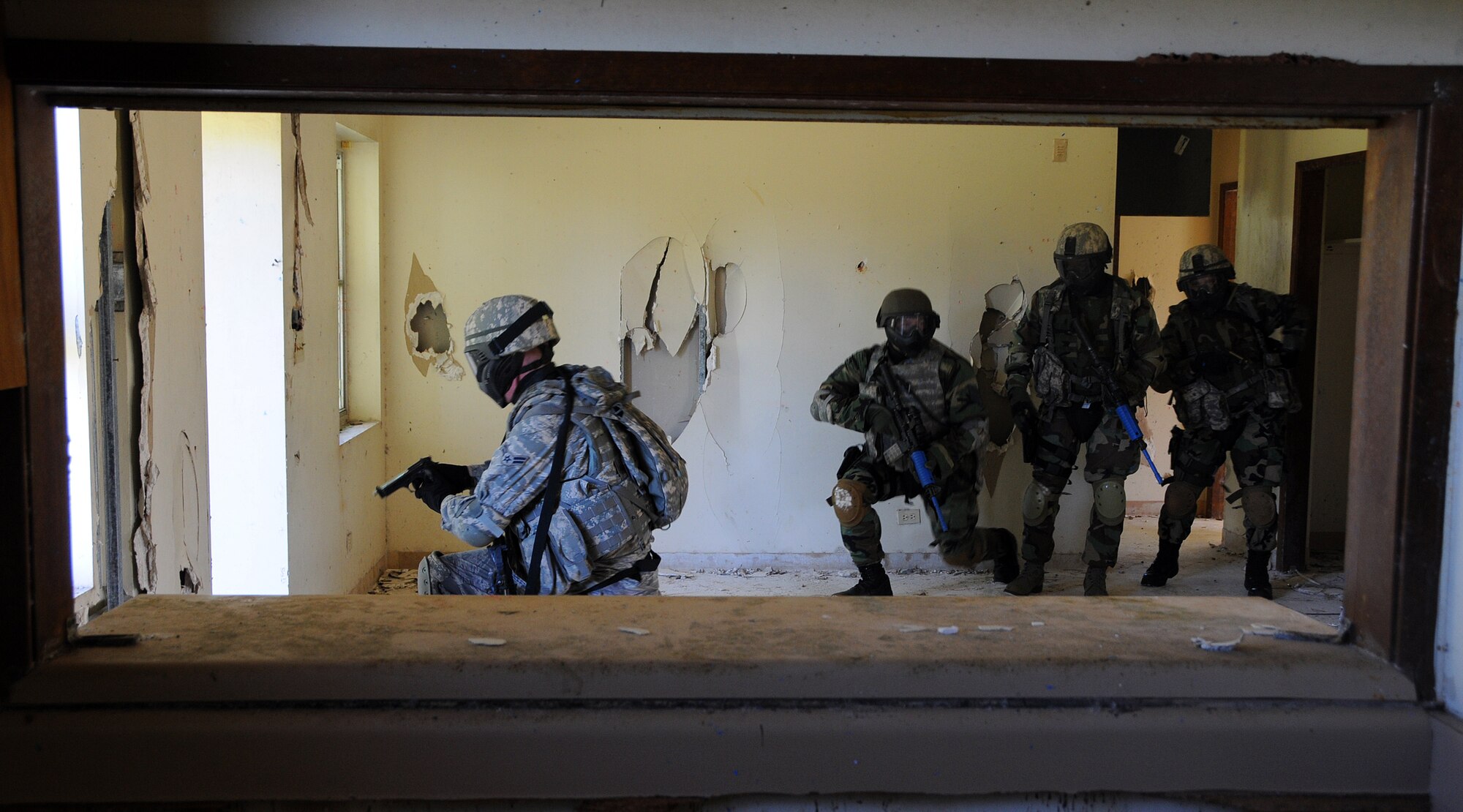 ANDERSEN AIR FORCE BASE, Guam - Airman 1st Class Jason Potts, 354th Eielson Security Forces Patrolman, takes a knee to guard a window while teammates from Kulis Air National Guard finish clearing the abandoned house here during Commando Warrior Urban Operations exercise 09-1 Jan. 31. The exercise used "simunitions," dye-filled rounds that fit in M4 or 9MM weapons, to train Airmen on team tactics and movement under fire in simulated combat environments. (U.S. Air Force photo by Airman 1st Class Courtney Witt)
