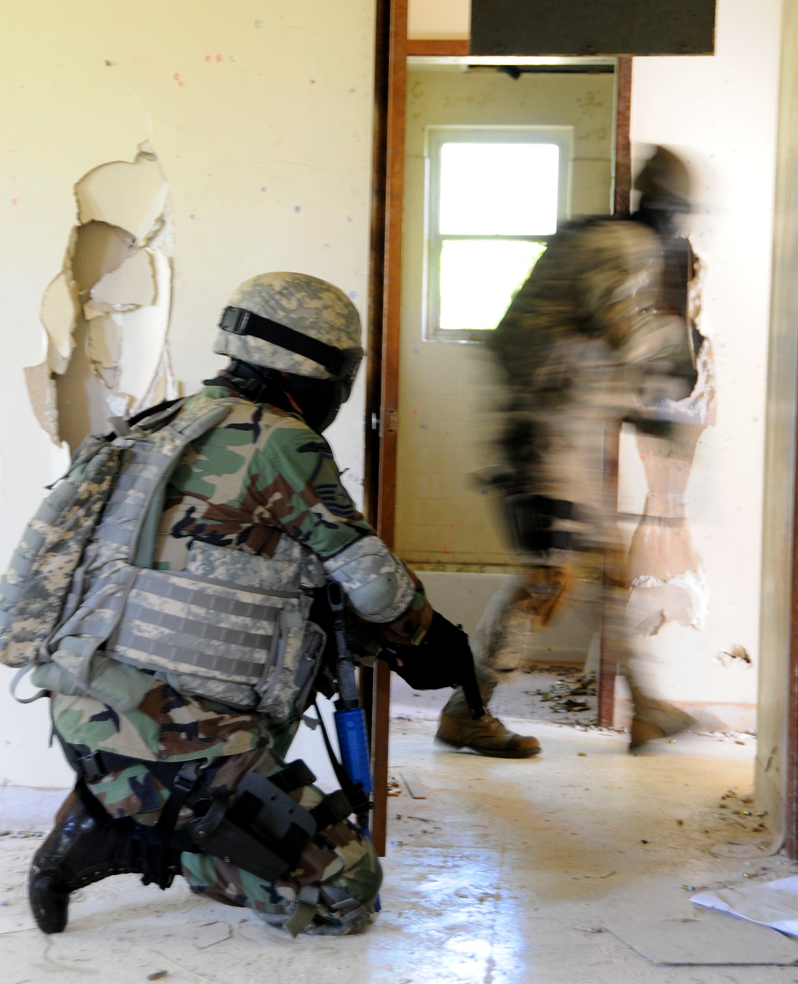 ANDERSEN AIR FORCE BASE, Guam - Master Sgt. Bryan Mooreberg, Squad Leader from Kulis Air National Guard, takes a knee as his partner, Airman 1st Class Evan Johnston, also of Kulis ANG, clears a room here during the Commando Warrior Urban Operations exercise 09-1Jan. 31. The noise, smoke and OPFOR personnel create a high stress environment especially when combined with the heat and humidity here on Guam will allow the students to improve the training within their organizations where climate conditions are vastly different. (U.S. Air Force photo by Airman 1st Class Courtney Witt)

