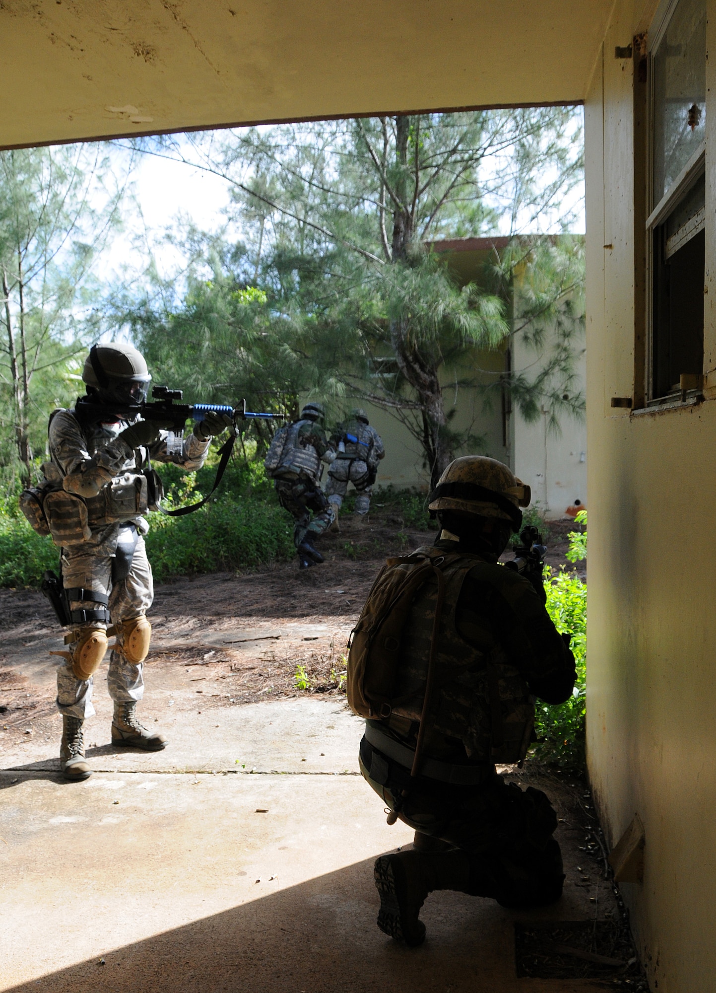 ANDERSEN AIR FORCE BASE, Guam - Staff Sgt. Travis Garrison takes a knee as Airman 1st Class Evan Johnston scans the side of the building for clearance to cross to the next house here during Commando Warrior Urban Operations exercise 09-1 Jan. 31. Both Security Forces members are out of the 176th Squadron from Kulis Air National Guard. Realism during the exercise is needed to allow students to understand the complicity of urban warfare. (U.S. Air Force photo by Airman 1st Class Courtney Witt)

