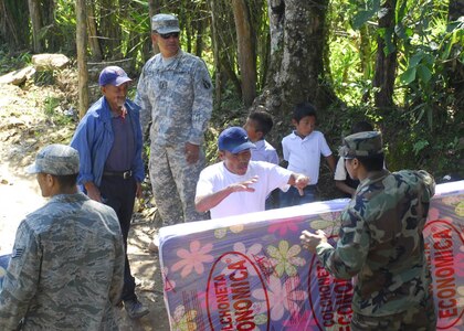 SOTO CANO AIR BASE, Honduras - Staff Sgt. Lancaster Ladore (right), Joint Task Force-Bravo, hands a mattress to a man in El Mangos, Honduras, Jan. 30.  Volunteers from JTF-B delivered more than 200 mattresses to people in three villages this week as part of a U.S. Southern Command initiative to replace items destroyed in recent floods.  (US Air Force photo/Tech. Sgt. Rebecca Danét)