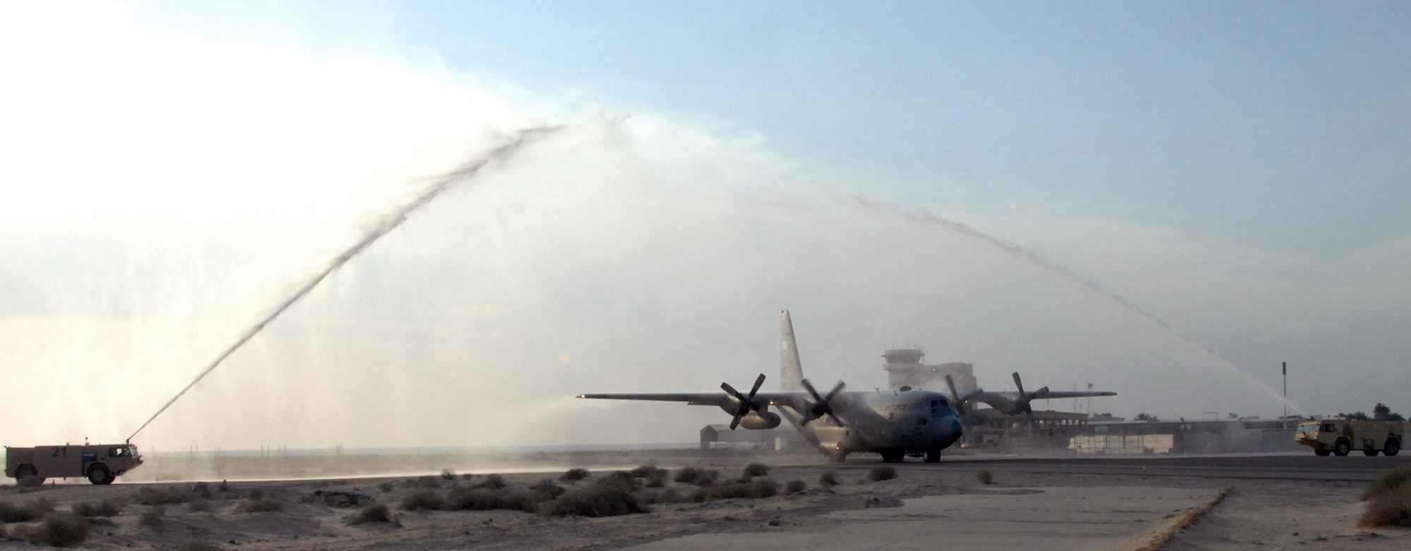 C-130 Hercules no. 1847 passes through the ceremonial water spray from two fire trucks at an air base in Southwest Asia after completing its final combat mission Jan. 28. After 47 years of service, the aircraft is being retired.  (U.S. Air Force photo/Senior Airman Courtney Richardson)