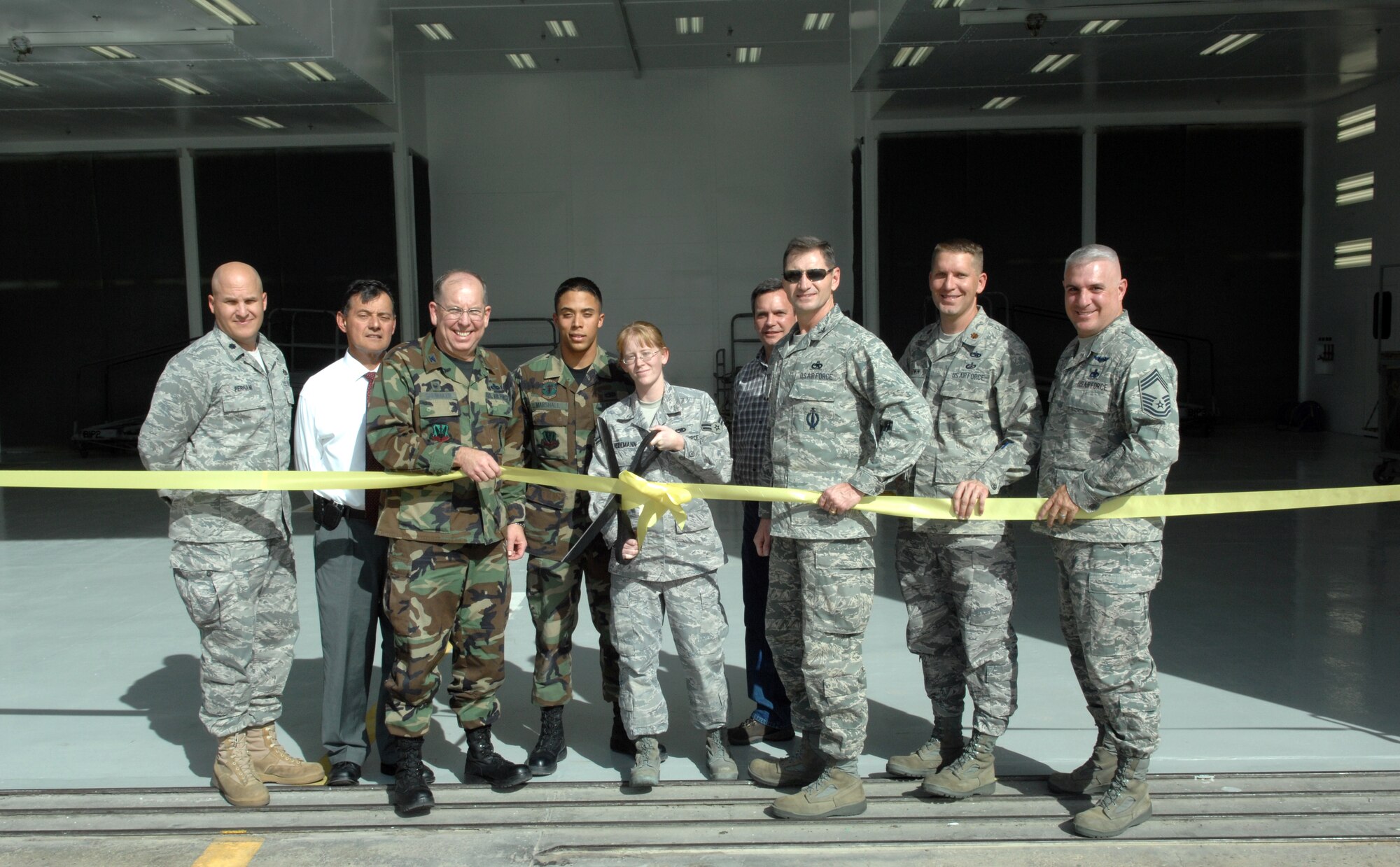 Col. Dennis Shumaker, the 355th Maintenance Group commander and members of the 355th Maintenance Squadron cut a commemorative ribbon during a ceremony here Thursday celebrating the renovation of a 50 year old corrosion barn, where more than 24 aircraft and parts are painted annually. 