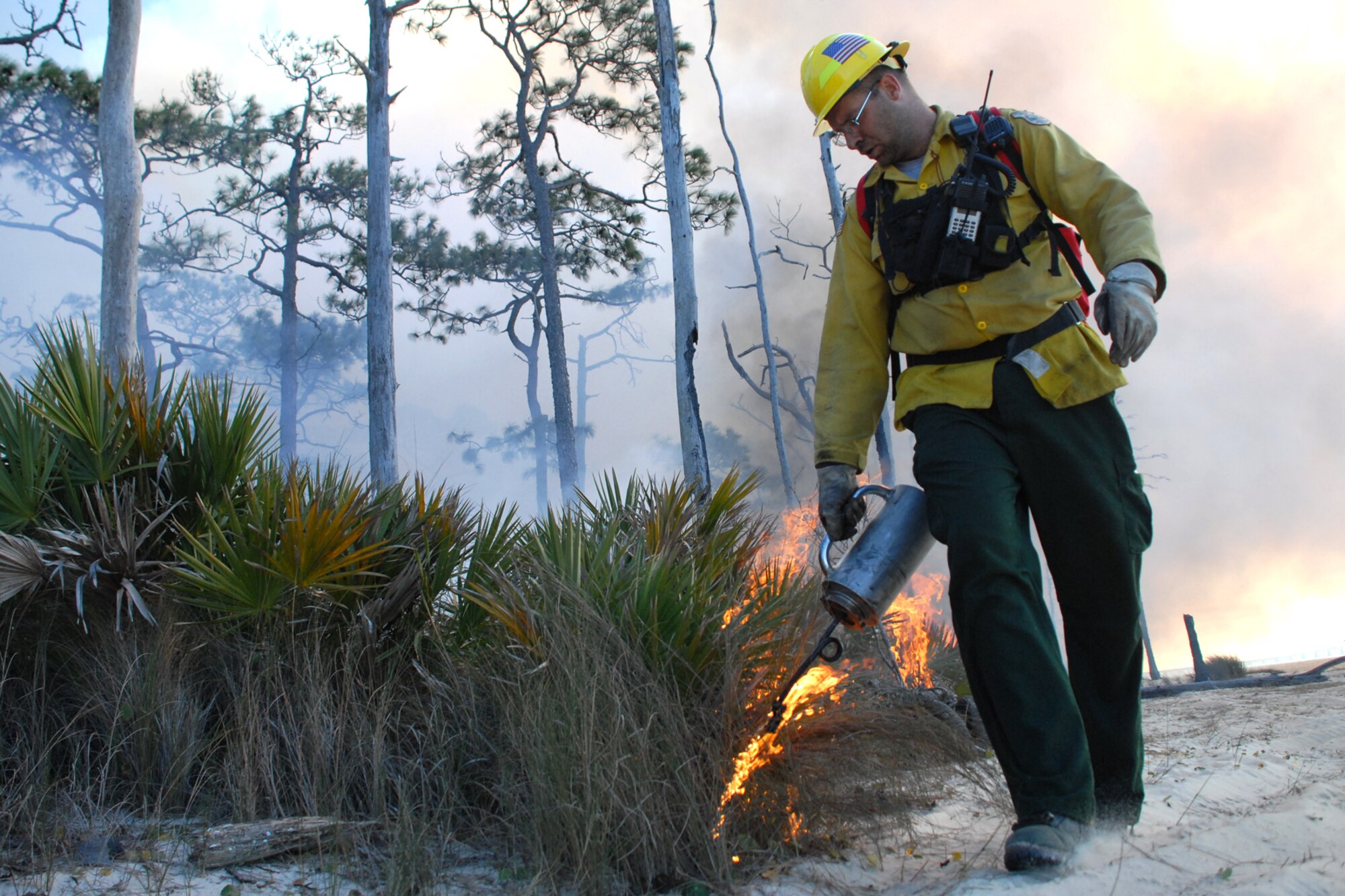 EGLIN AIR FORCE BASE, Fla. -- David Grimm, a Jackson Guard forestry technician and wildland fire specialist, uses a fire drip can to start a fire line during a prescribed burn at White Point, an 85-acre recreation area on the Choctawhatchee Bay Jan. 29. Many native plants and animal species depend on Eglin's fire-dependent long-leaf pine ecosystem, 11 of which are federally protected. Endangered species such as the red-cockaded woodpecker, depend on fire that is typically caused by either lightning strikes or Eglin's resident fire managers to survive. As of the 2008 control burn season, Jackson Guard's five-year average is 73,000 acres burned annually. (U.S. Air Force Photo by Staff Sgt. Mike Meares)