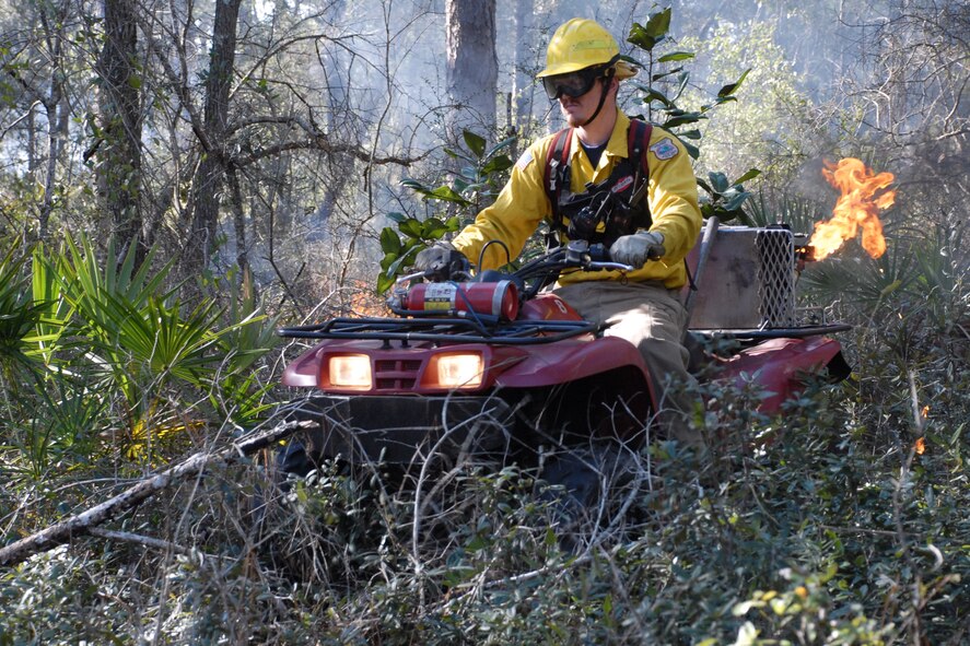 EGLIN AIR FORCE BASE, Fla. -- Ryan Campbell, a Jackson Guard forestry technician and wildland fire specialist, navigates an all-terrain vehicle through a wooded area dragging a fire drip line in his path to start a prescribed burn at White Point, an 85-acre recreation area on the Choctawhatchee Bay Jan. 29. Many native plants and animal species depend on Eglin's fire-dependent long-leaf pine ecosystem, 11 of which are federally protected. Endangered species such as the red-cockaded woodpecker, depend on fire that is typically caused by either lightning strikes or Eglin's resident fire managers to survive. As of the 2008 control burn season, Jackson Guard's five-year average is 73,000 acres burned annually. (U.S. Air Force Photo by Staff Sgt. Mike Meares) 
