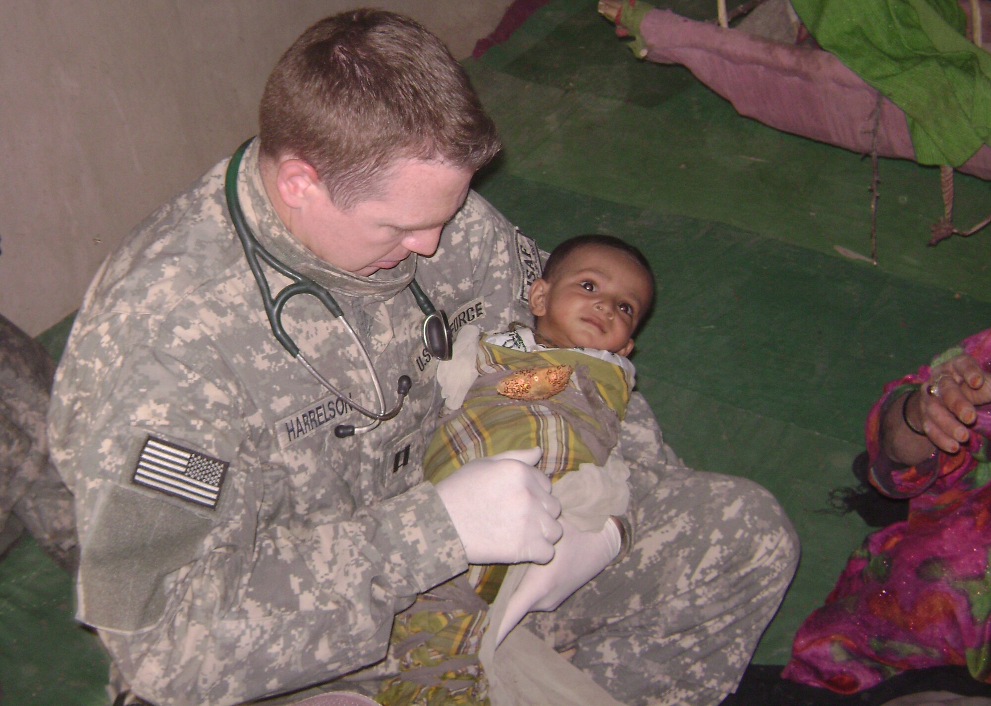 During an eight-month deployment to Afghanistan, Capt. Timothy Harrelson, family practice physician assistant, 35th Medical Operations Squadron, exams a 10-month-old child. Captain Harrelson, an Indian Land, S.C., native, was awarded the Bronze Star for his  efforts during his deployment. (Courtesy photo)