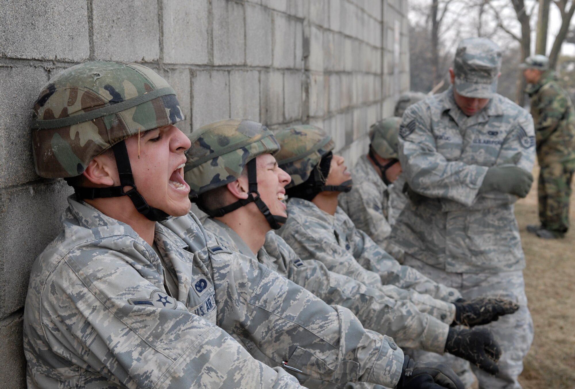 Airman Albert Rodriguez, (Left) and Airman 1st Class Thomas Dunbar perform wall-sits after low-crawling up a hill during the 51st Security Forces Squadron combat readiness course Jan. 22 on Osan AB. Newly arriving security forces Airmen go through a six-day combat readiness course designed to prepare SF Airmen, giving them the tools needed to perform the mission.  Airmen Rodriguez and Dunbar are assigned to the 51st SFS. (U.S. Air Force photo/Staff Sgt Brian Ferguson)