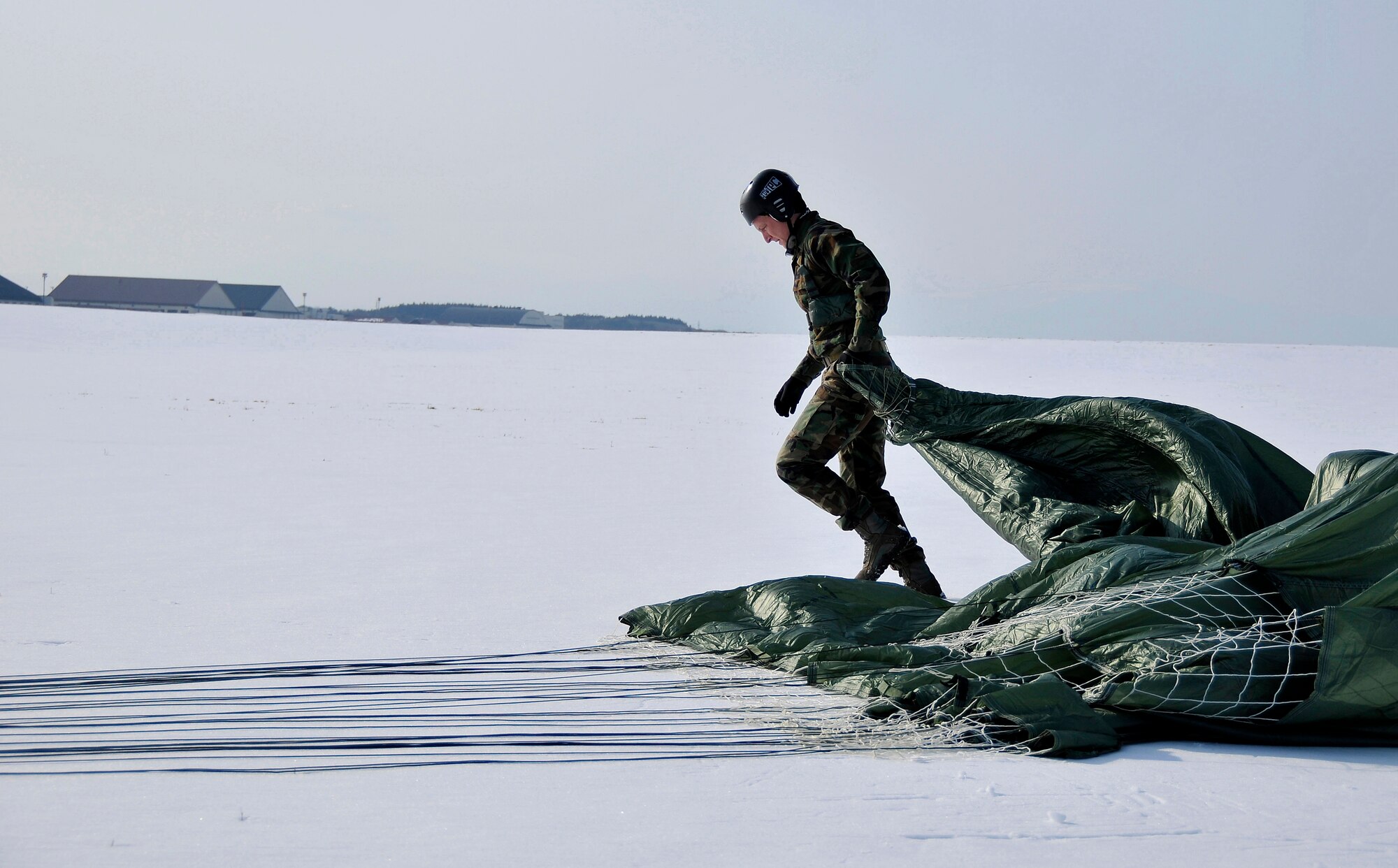 MISAWA AIR BASE, Japan -- Staff Sgt. Benjamin Thomas, 35th Operations Support Squadron Survival, Evasion, Resistance and Escape instructor, drags his parachute over to his team after jumping out of a C-130 Hercules at 1,250 feet during training Jan. 22, 2009.  The jump provided a training opportunity for the aircrew and the special forces personnel.  (U.S. Air Force photo by Senior Airman Chad Strohmeyer)
