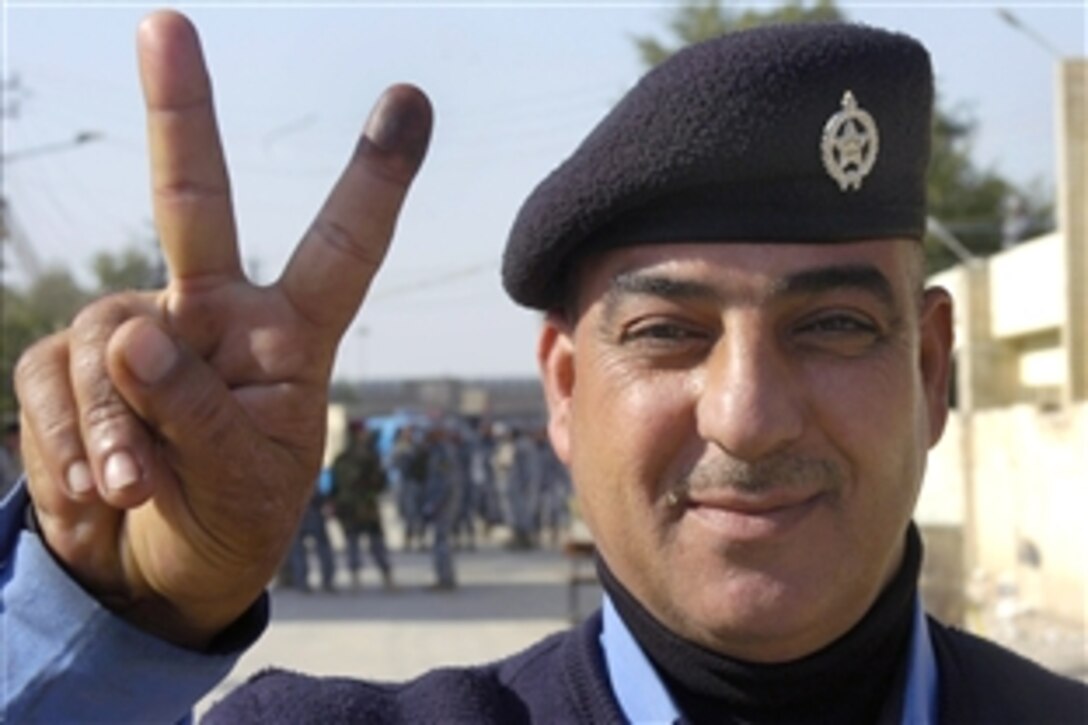 An Iraqi police officer gives a “peace” sign as he shows his ink-stained finger after leaving a polling station in the New Baghdad district of eastern Baghdad, Jan. 28, 2009. The Iraqi government is holding early elections to enable Iraqi Security Forces and others with special needs to vote in provincial elections, scheduled for Jan. 31 for the general public.