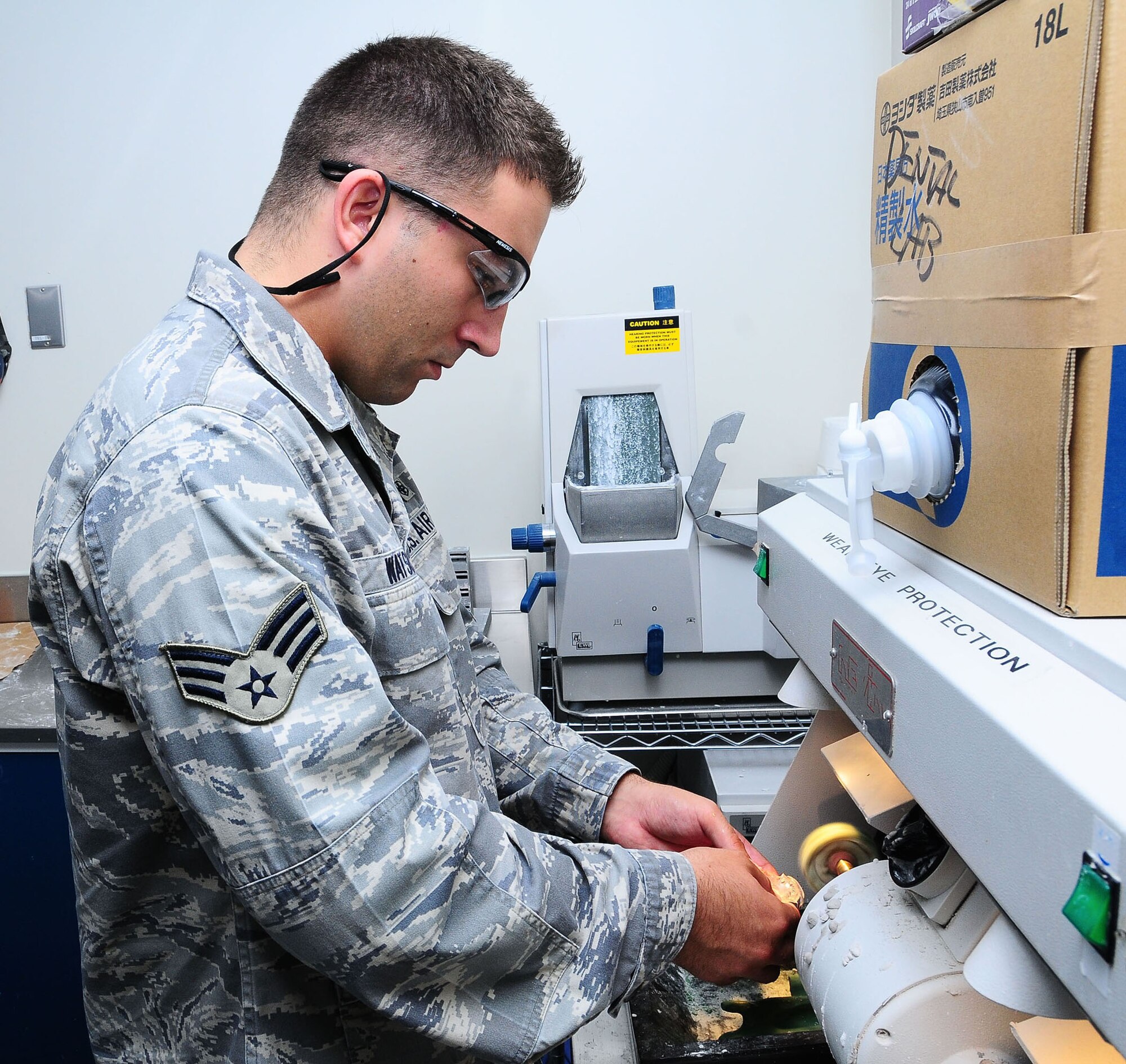 YOKOTA AIR BASE, Japan--Senior Airman Mike Watson, 374th Dental Squadron dental laboratory technician, polishes a retainer using a pumice machine June 26. The dental laboratory specializes in making crowns, dentures, retainers, and dentures for their patients.  (U.S. Air Force photo/Airman 1st Class Sean Martin)