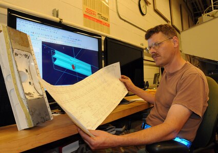 Tech. Sgt. Stephen Sarkany examines mechanical drawings used to created computerized models of parts to be fabricated in the metals technology shop here July 1. The computer model is translated into programming codes and loaded into drilling machines which create aircraft parts from unformed metal. Sergeant Sarkany is the swing shift supervisor for the 437 MXS metals technology shop. (U.S. Air Force photo/Staff Sgt. Daniel Bowles)