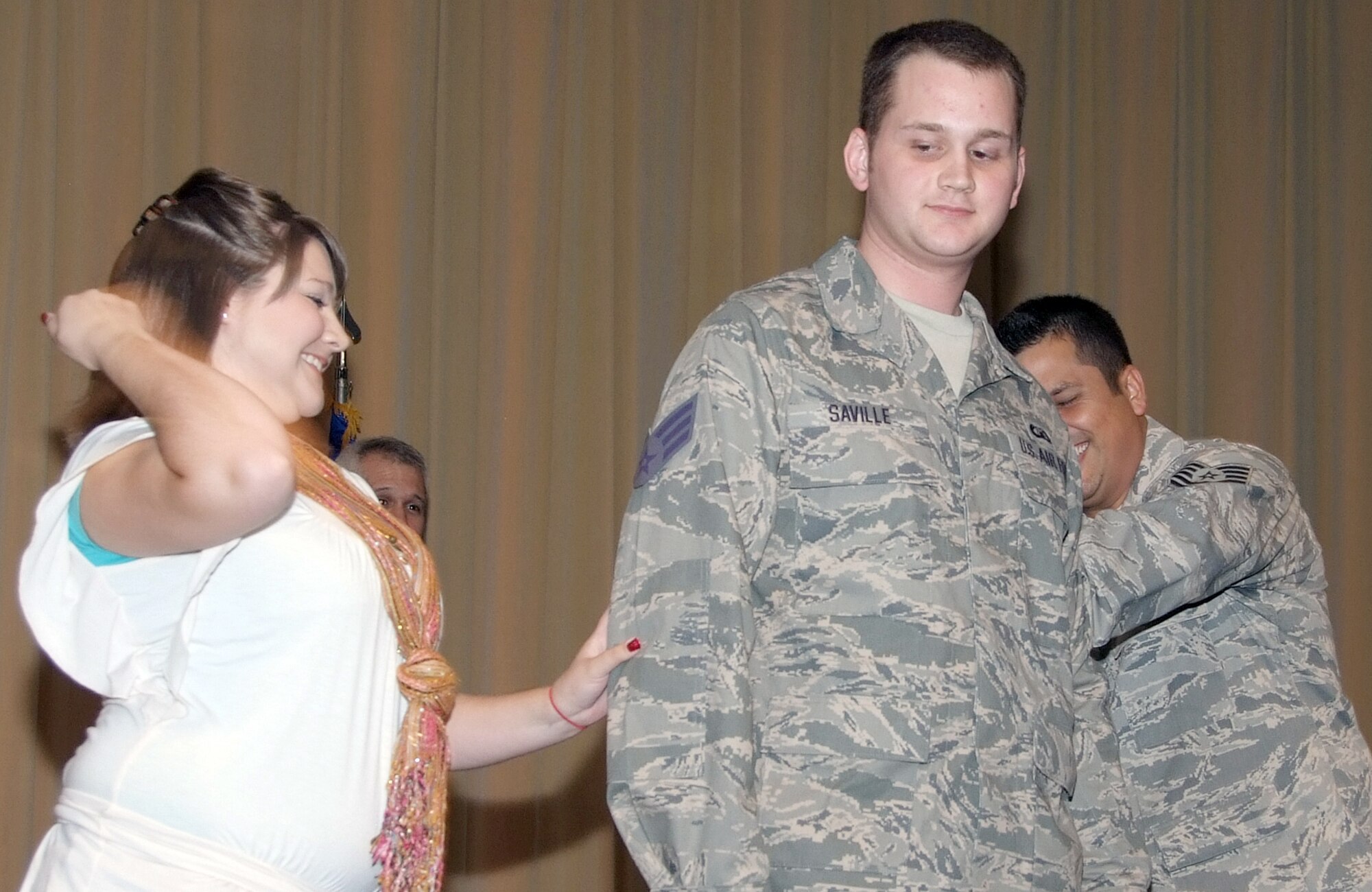 Joshua Saville gets his new Senior Airman stripes “tacked” on by his girlfriend, Beth Lewis, left, and his supervisor, Tech. Sgt. Patrick Colclasure, during a wing recognition ceremony held June 30 in the Base Auditorium at Vance AFB. Airman Saville and Sergeant Colclasure are air traffic controllers with the 71st Operations Support Squadron. (U.S. Air Force photo/ Terry Wasson)