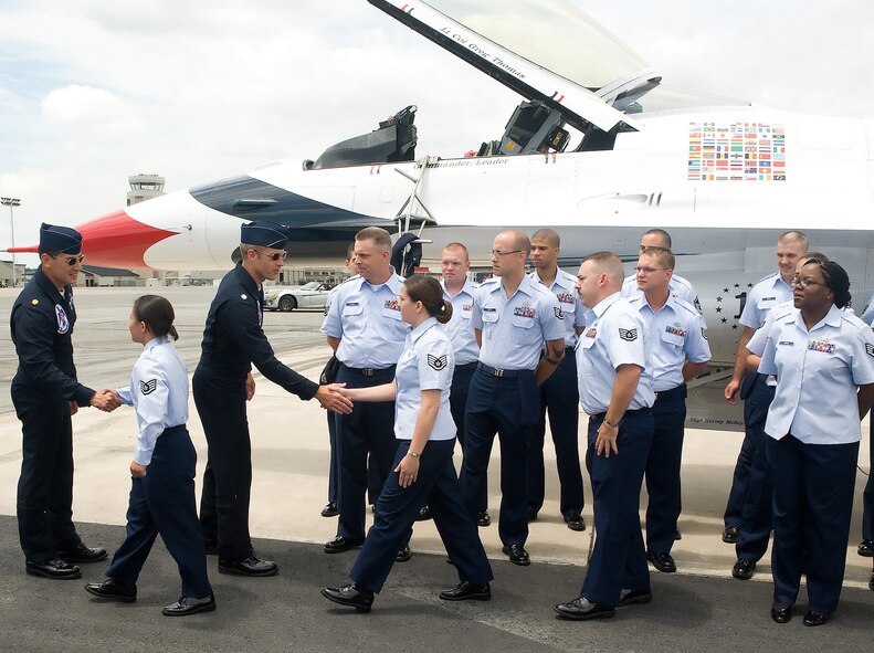 Two U.S. Air Force Thunderbirds Demonstration Team pilots congratulate Team Dover Airmen after administering a re-enlistment oath for the ceremony June 19 at Dover Air Force Base. Sixteen Airmen, consisting of active-duty and reservists, re-enlisted. (U.S. Air Force photo/Tom Randle)