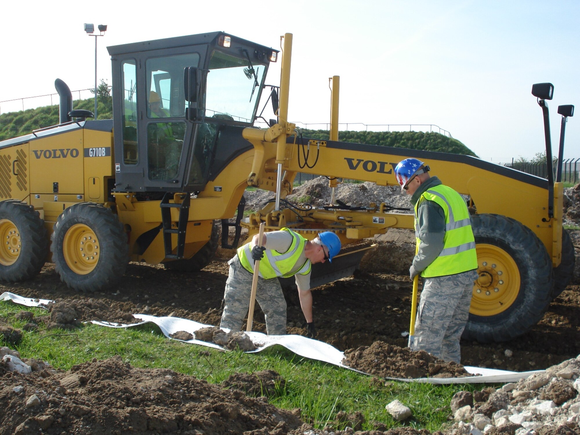 RAF FELTWELL, England--TSgt Thomas Riggsbee, NCOIC, Structures, 86th Construction and Training Squadron's Military Construction Flight, and SSgt Raymond Stokes, NCOIC, Engineering, 86th CTS/MCF, and SSgt Bobby Martin, Pavements & Equipment Operator, 86th CTS/MCF, determine proper width of material during grading operations for a perimeter road at RAF Feltwell. (USAF photo)
