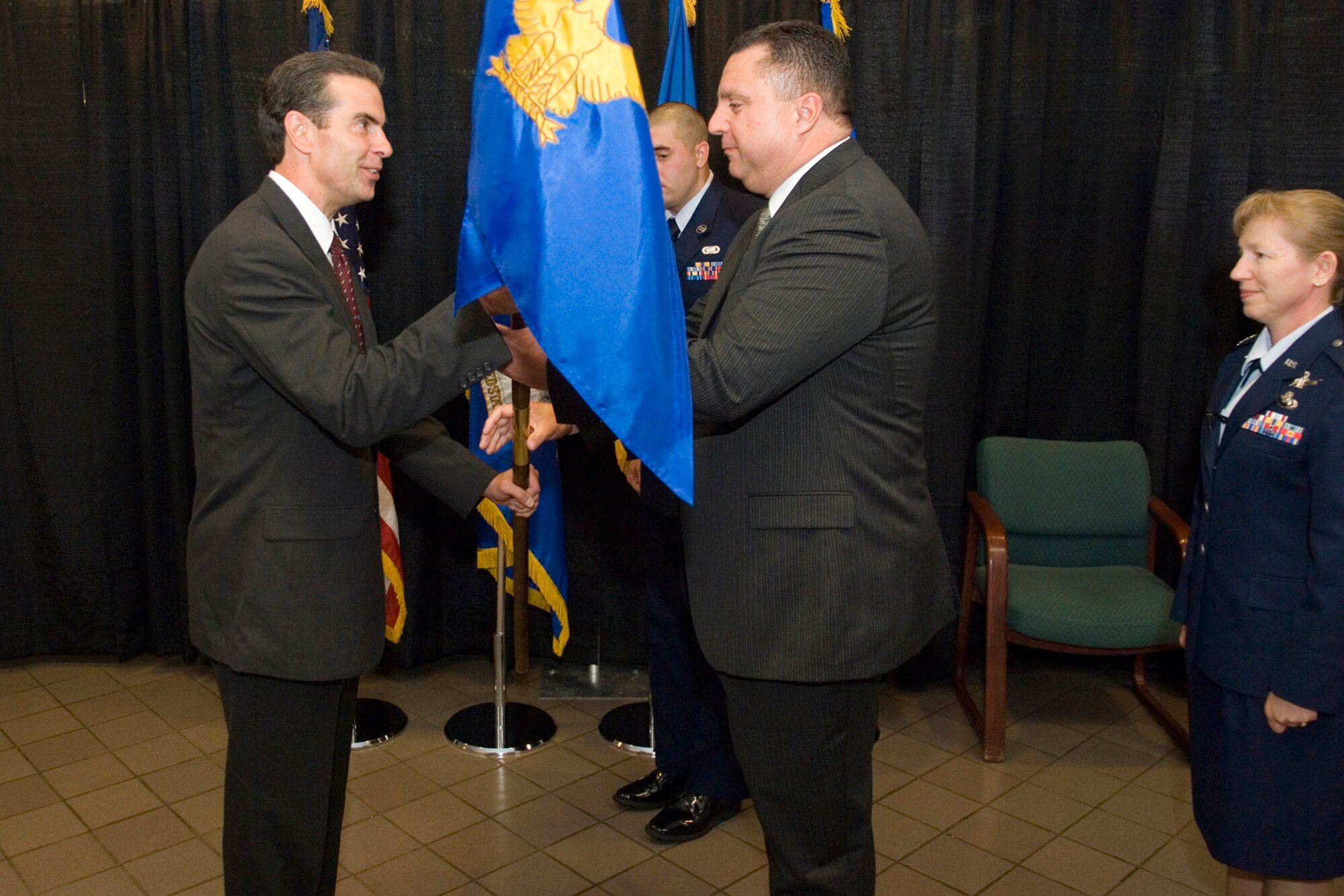 Ron Mason (left), director of the 653rd Electronic Systems Wing, passes the 753rd Electronic Systems Group command guidon to Ronnie Carter in a change of leadership ceremony June 25.  Mr. Carter, who had previously served as director of the 853 ELSG, took over for Col. Leslie Blackham (right), who has moved on to a staff position within the Office of the Secretary of Defense in the Pentagon.  (USAF Photo/Rick Berry)