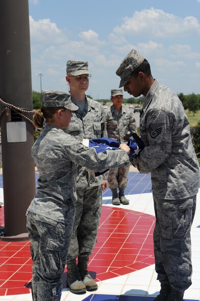 DYESS AIR FORCE BASE, Texas – Dyess Honor Guard members Staff Sgt. Raul Gonzalez (back) and Airman First Class Tera Defrias (front) fold the flag as Master Sgt. Robert Fournier (center) looks on during a retreat ceremony July 2 at the Dyess parade grounds here. A retreat ceremony signifies the end of a duty day; and in this special circumstance pays tribute to the July Fourth holiday and celebrates our countries’ independence. (U.S. Air Force photo by Senior Airman Jennifer Romig)