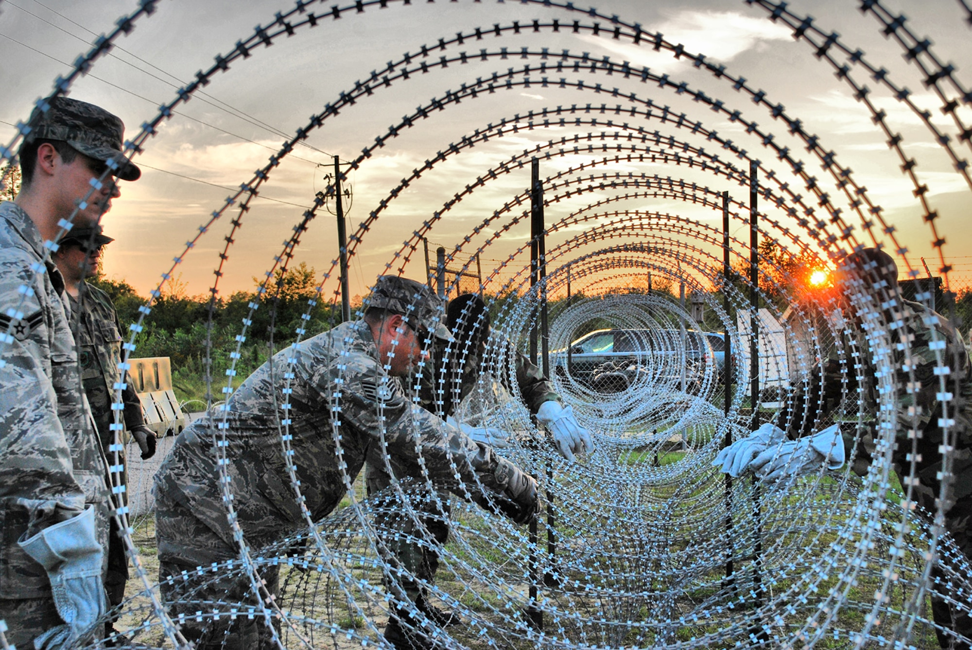 Airmen from the 621st Contingency Response Wing at McGuire Air Force Base, N.J., construct razor wire fences around their camp perimeter June 24 during a noncombatant evacuation exercise at Mackall Army Airfield, N.C.  CRW Airmen manned defensive fighting positions as the exercise scenario became "hostile." (U.S. Air Force photo/Staff Sgt. Nicholas Phelps)