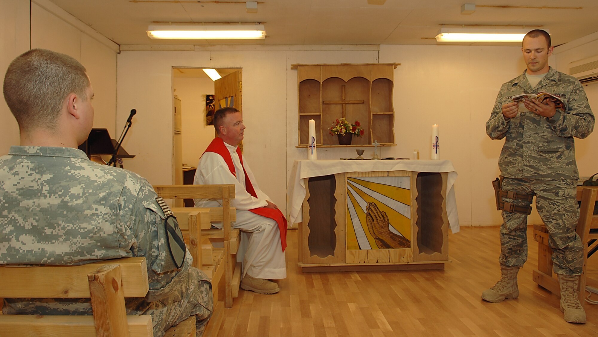 FORWARD OPERATING BASE MCHENRY, Iraq – Staff Sgt. Seth Clark, 506th Air Expeditionary Group chaplain assistant, reads a scripture during a Catholic Mass as Chaplain (Lt. Col.) Mark Rowan listens. Sergeant Clark, a Morgantown, W.V., native deployed from the 80th Training Wing Chapel, Goodfellow AFB, Texas, and Chaplain Rowan, a Long Island, N.Y., native deployed from the 374th Air Wing Chapel, Yokota Air Base, Japan, fly aboard military helicopters to isolated bases to provide religious services to Soldiers. (U.S. Air Force photo / Senior Airman Jessica Lockoski)