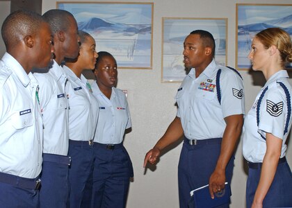Staff Sgt. Charles A. Lane, 343rd Training Squadron, and Tech. Sgt. Jennifer Willemin, 37th Training Group, make spot corrections on technical training school students at the Live Oak dining facility June 26. Sergeants Lane and Willemin are Military Training Leaders. (U.S. Air Force photo/Sid Luna)                               