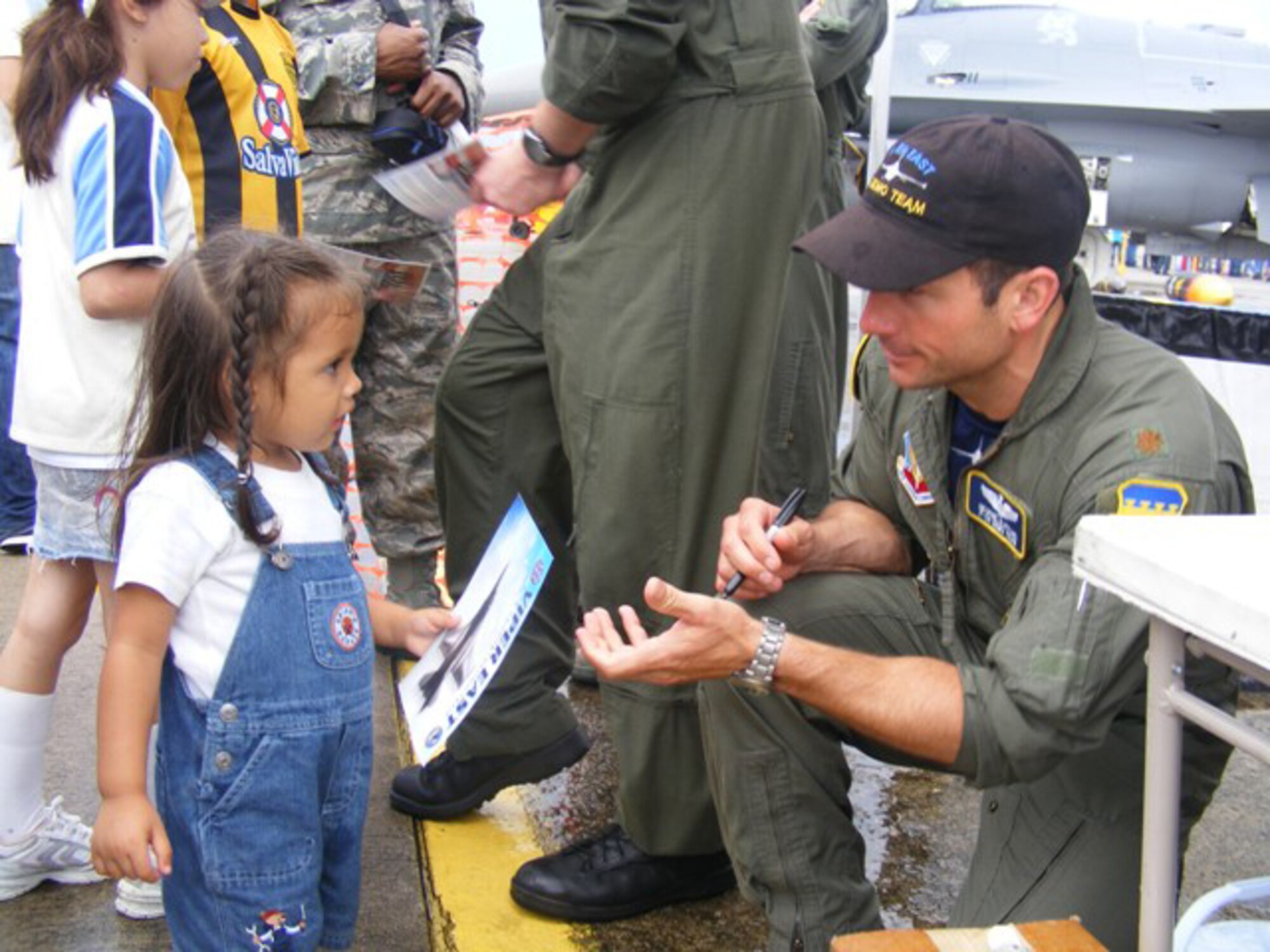 Maj. George Clifford, Viper East F-16 Demo Team pilot, signs an autograph for a Honduran girl at an air show here June 20. More than 30 Airmen participated at the international air show June 20-21. The more than $35,000 proceeds from the show will help build a children?s intensive care unit at a local hospital. 