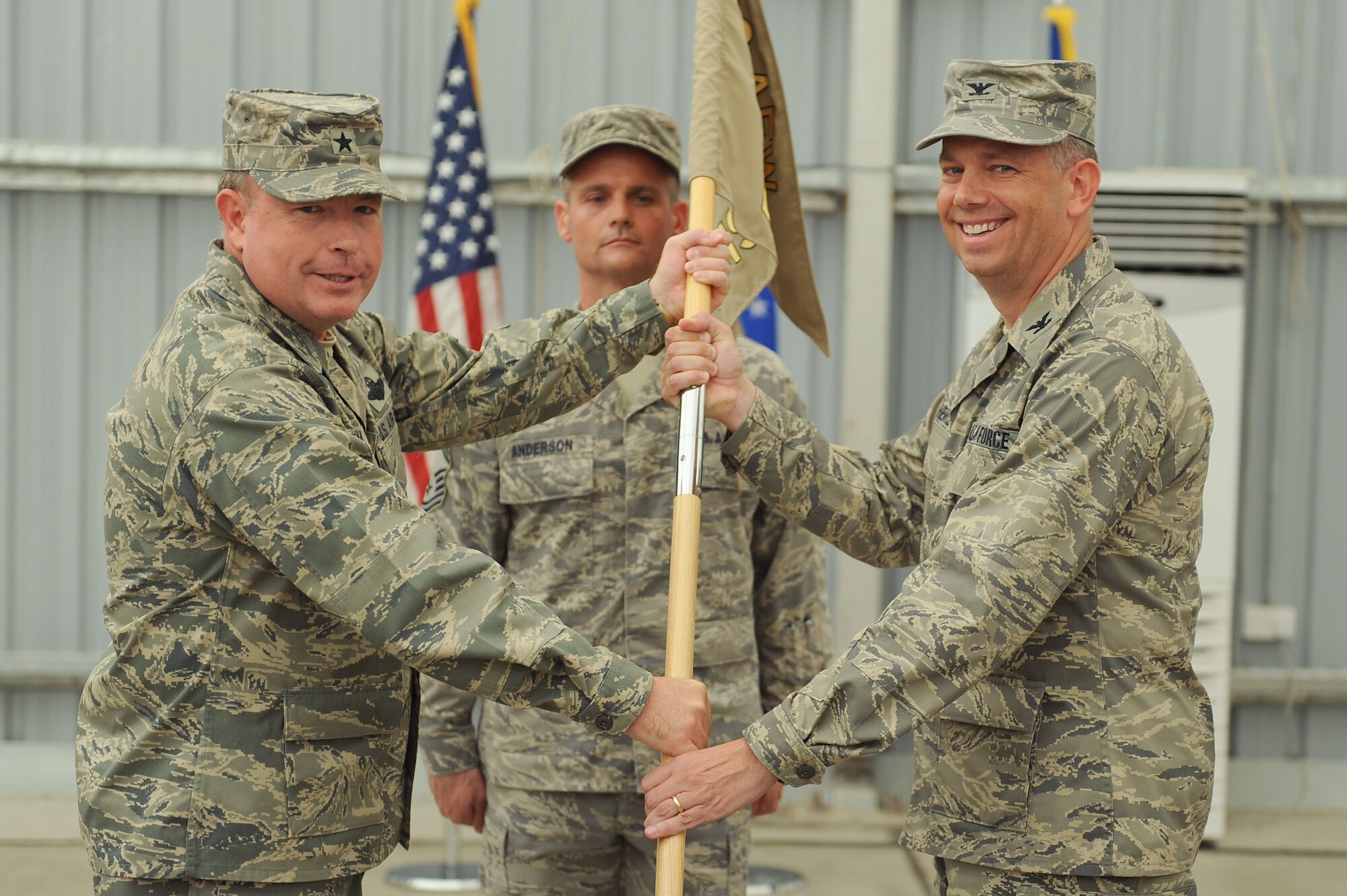 SOUTHWEST ASIA - Brig. Gen. Bryan Benson, 380th Air Expeditionary Wing, commander, passes the guidon of the 380th Expeditionary Mission Support Group to Col. Eric Pierce as he takes command, June 30 at an undisclosed location in Southwest Asia. Colonel Pierce comes from the Pentagon joining the 380th Air Expeditionary Wing to lead the 380th EMSG. (U.S. Air Force photo by Senior Airman Brian J. Ellis) (Released)