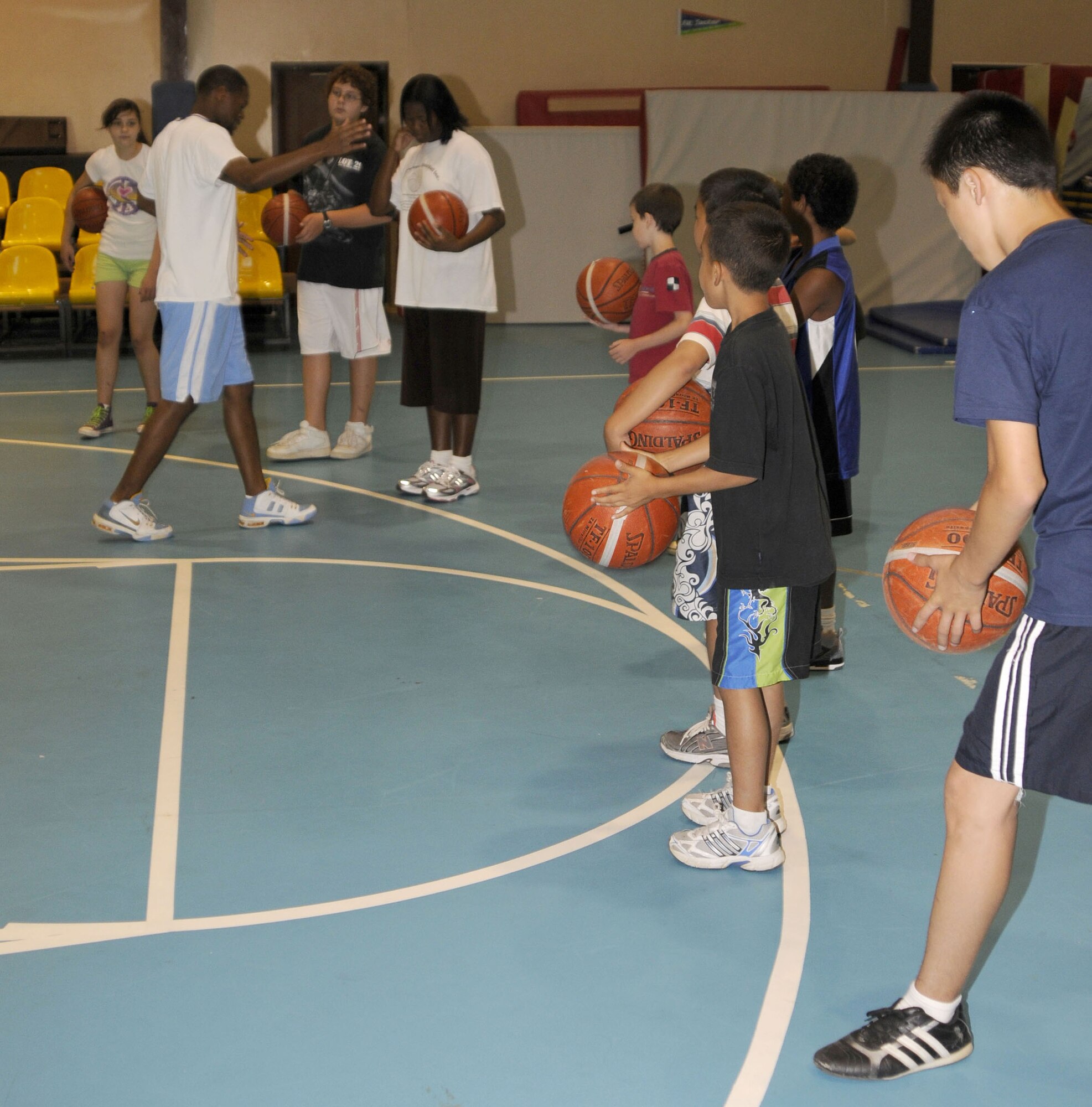 Basketball players watch and listen as Tim Visor, Youth Programs assistant, demonstrates the steps of a lay-up Tuesday, July 1, 2009 during a basketball camp at Incirlik Air Base, Turkey. The camp, which ran the entire week, is one of several camps and recreation trips available for children during their summer. For more information about activities call YP at 676-6670. (U.S. Air Force photo/Airman 1st Class Amber Russell)