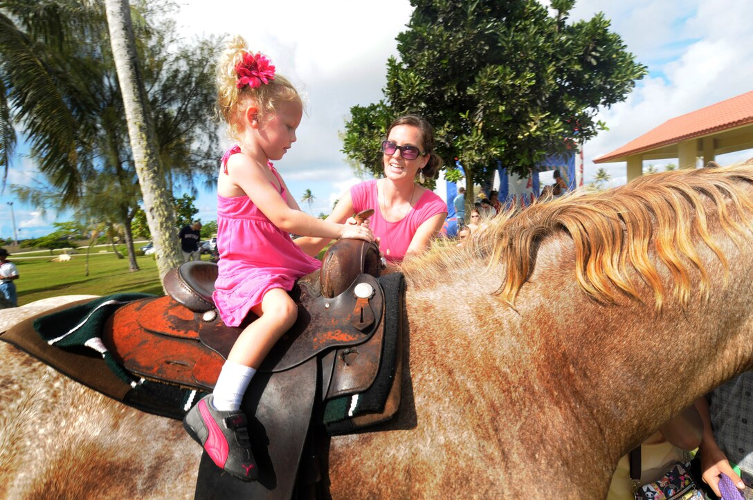ANDERSEN AIR FORCE BASE, Guam - With an assist from mom Nellie Boyer, two-year-old Analia Boyer takes a horseback ride during Andersen's Freedom Fest 2009 here July 2. Other activities included face painting, water slide, a bouncy castle, a dunking booth, paintball, pie eating contests.   (U.S. Air Force photo by Tech. Sgt. Michael Boquette)