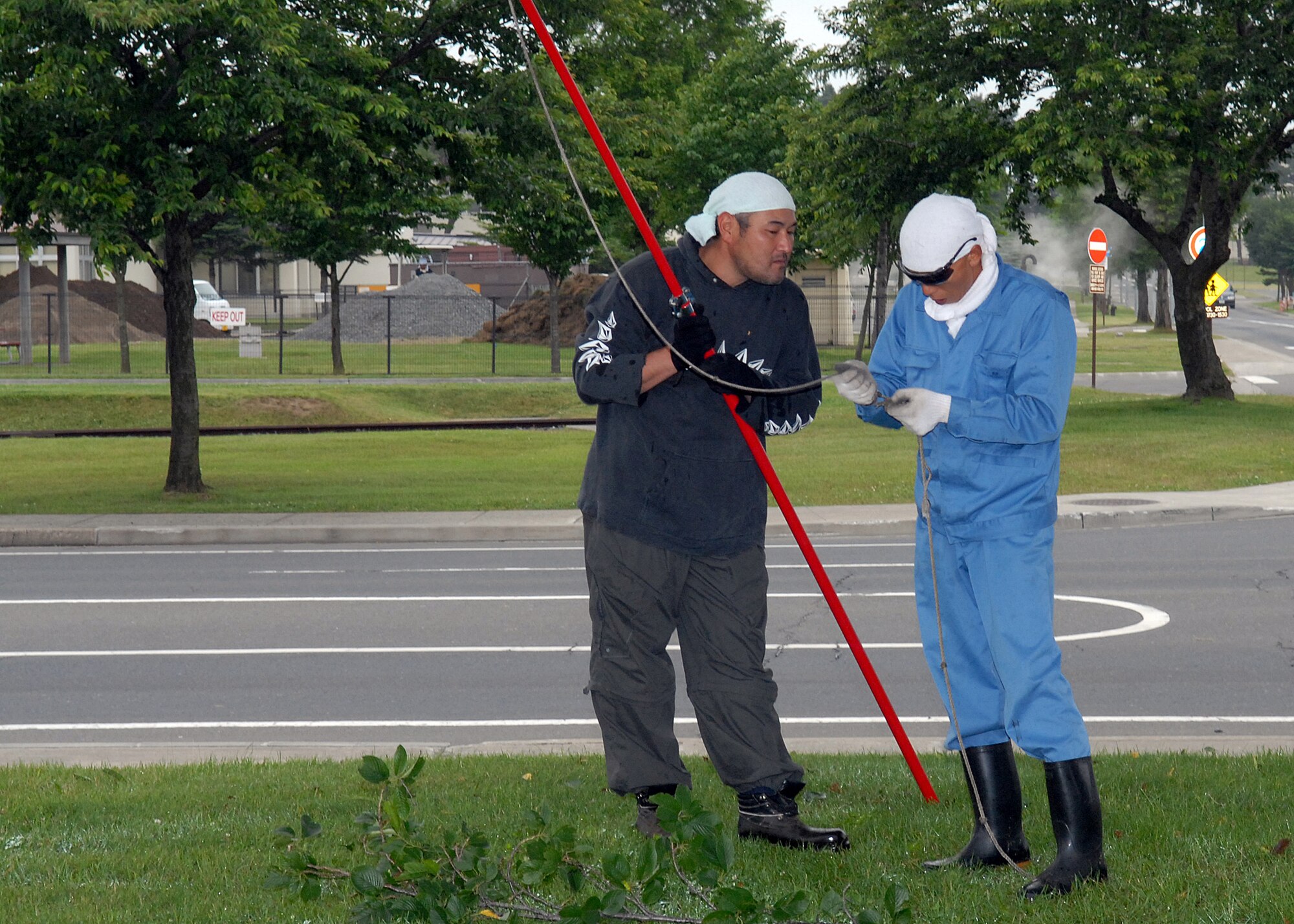 MISAWA AIR BASE, Japan -- Japanese contractors fix a broken tree trimmer line July 2 near Friendship Blvd. Contractors have been trimming trees on Friendship Blvd since July 27. Low hanging branches require trimming to prevent safety hazards. (Air Force photo/Staff Sgt. Phillip Butterfield)  
 
