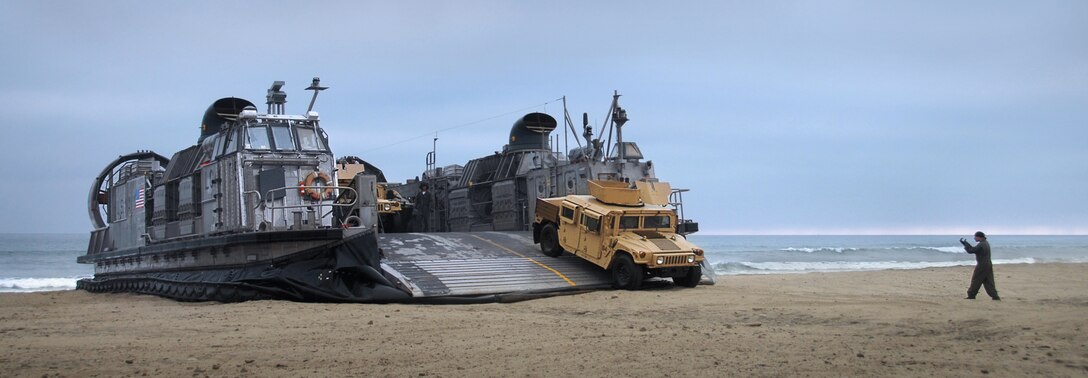 First Light Armored Reconnaissance Battalion vehicles disembark from a Navy air-cushioned landing craft to conduct the tactical recovery of a simulated missing pilot here July 2. The LAR detachment is part of Battalion Landing Team 2/4, the 11th Marine Expeditionary Unit’s ground combat element. The MEU, part of the Bonhomme Richard Amphibious Ready Group, is conducting its first pre-deployment exercise at sea with its Navy counterpart, Amphibious Squadron 7. The Navy and Marine Corps team is testing interoperability before a deployment certification exercise later this summer.