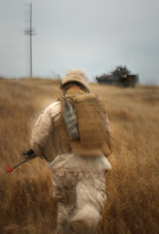 Cpl. Eric Laisure, 24, hurries back to his ride, a light-armored vehicle, after members from his 1st Light Armored Reconnaissance Battalion recovered a simulated missing pilot here July 2. The LAR detachment is part of Battalion Landing Team 2/4, the 11th Marine Expeditionary Unit’s ground combat element. The MEU, part of the Bonhomme Richard Amphibious Ready Group, is conducting its first pre-deployment exercise at sea with its Navy counterpart, Amphibious Squadron 7. The Navy and Marine Corps team is testing interoperability before a deployment certification exercise later this summer. Laisure hails from Hesperia, Mich.