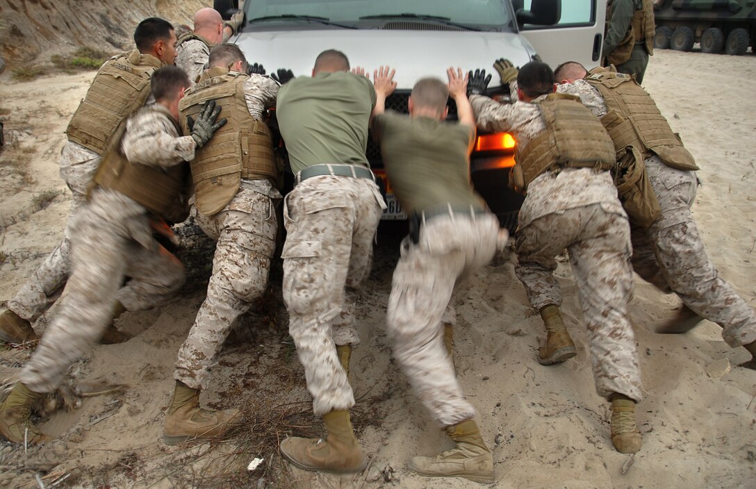 Marines from 1st Light Armored Reconnaissance Battalion, after conducting the tactical recovery of a simulated missing pilot here July 2, pause training to help push a van stuck in the sand near their beach landing site. After freeing the van, the LAR Marines loaded their light-armored vehicles onto Navy air-cushioned landing craft heading back to USS Bonhomme Richard. The LAR detachment is part of Battalion Landing Team 2/4, the 11th Marine Expeditionary Unit’s ground combat element. The MEU, part of the Bonhomme Richard Amphibious Ready Group, is conducting its first pre-deployment exercise at sea with its Navy counterpart, Amphibious Squadron 7. The Navy and Marine Corps team is testing interoperability before a deployment certification exercise later this summer.