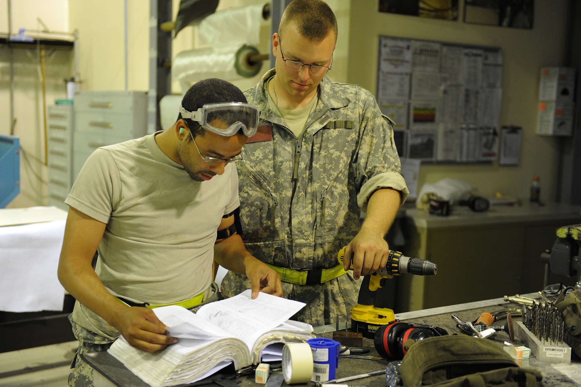 SOUTHWEST ASIA - Staff Sgt. Gary Pitcher and Senior Airman Benjamin Evans, 380th Expeditionary Maintenance Squadron, aircraft structural maintenance craftsmen, review a manual prior to preparing a panel for a KC-10 Extender, June 17 at an undisclosed location in Southwest Asia. The new panel will replace a panel that was corroding from the inside. (U.S. Air Force photo by Senior Airman Brian J. Ellis) (Released)