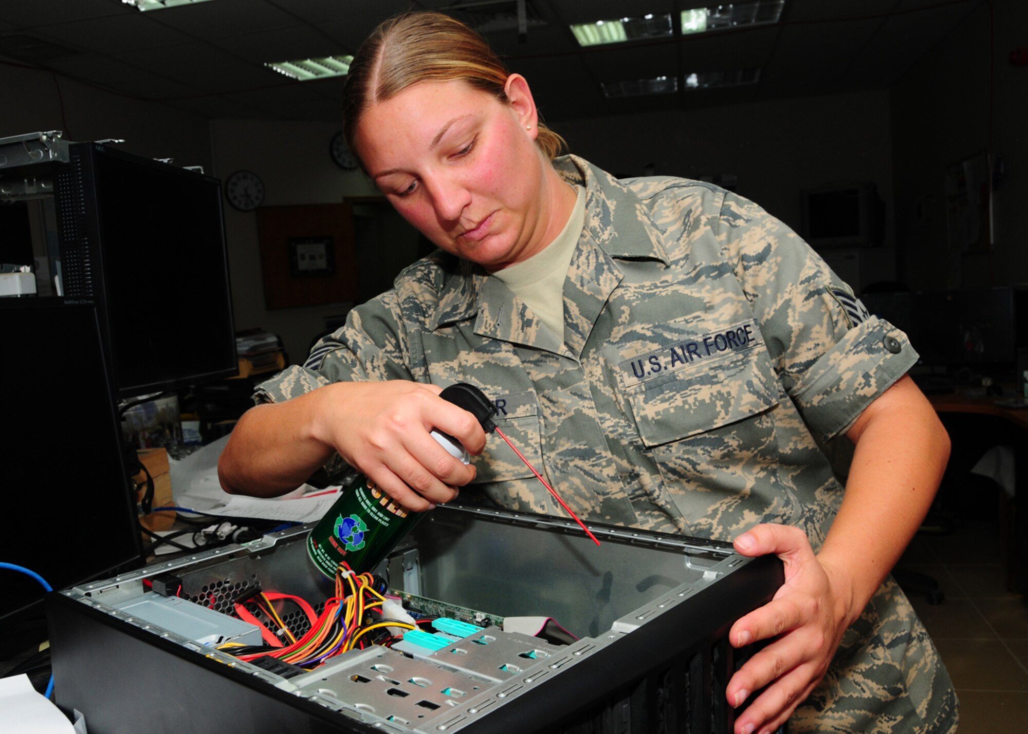 SOUTHWEST ASIA -- Staff Sgt. Sherri Strifler, 386th Expeditionary Communications Squadron, uses canned air to blow out sand and normal day-to-day dust build-up at an air base in Southwest Asia, July 1. The cleaning of the computers allows proper cycling of fans for correction operation and less video card, hard drive and power supply failures. Sergeant Strifler is deployed from Langely Air Force Base, Va., and hails from Las Vegas. (U.S. Air Force photo/Senior Airman Courtney Richardson)
