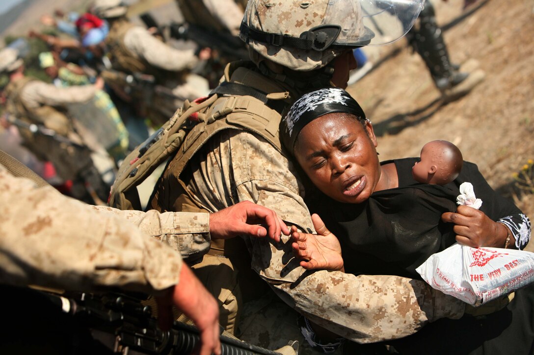 Marines with Battery A, 1st Battalion, 11th Marines, calm role players before providing medical care, food and water in a humanitarian aid exercise here July 5, 2009. The battery is attached to the ground combat element of the 11th Marine Expeditionary Unit, which is scheduled to deploy this fall. The MEU, part of the Bonhomme Richard Amphibious Ready Group, is conducting its first pre-deployment exercise at sea with its Navy counterpart, Amphibious Squadron 7. This Navy and Marine Corps team is testing interoperability before a deployment certification exercise later this summer.