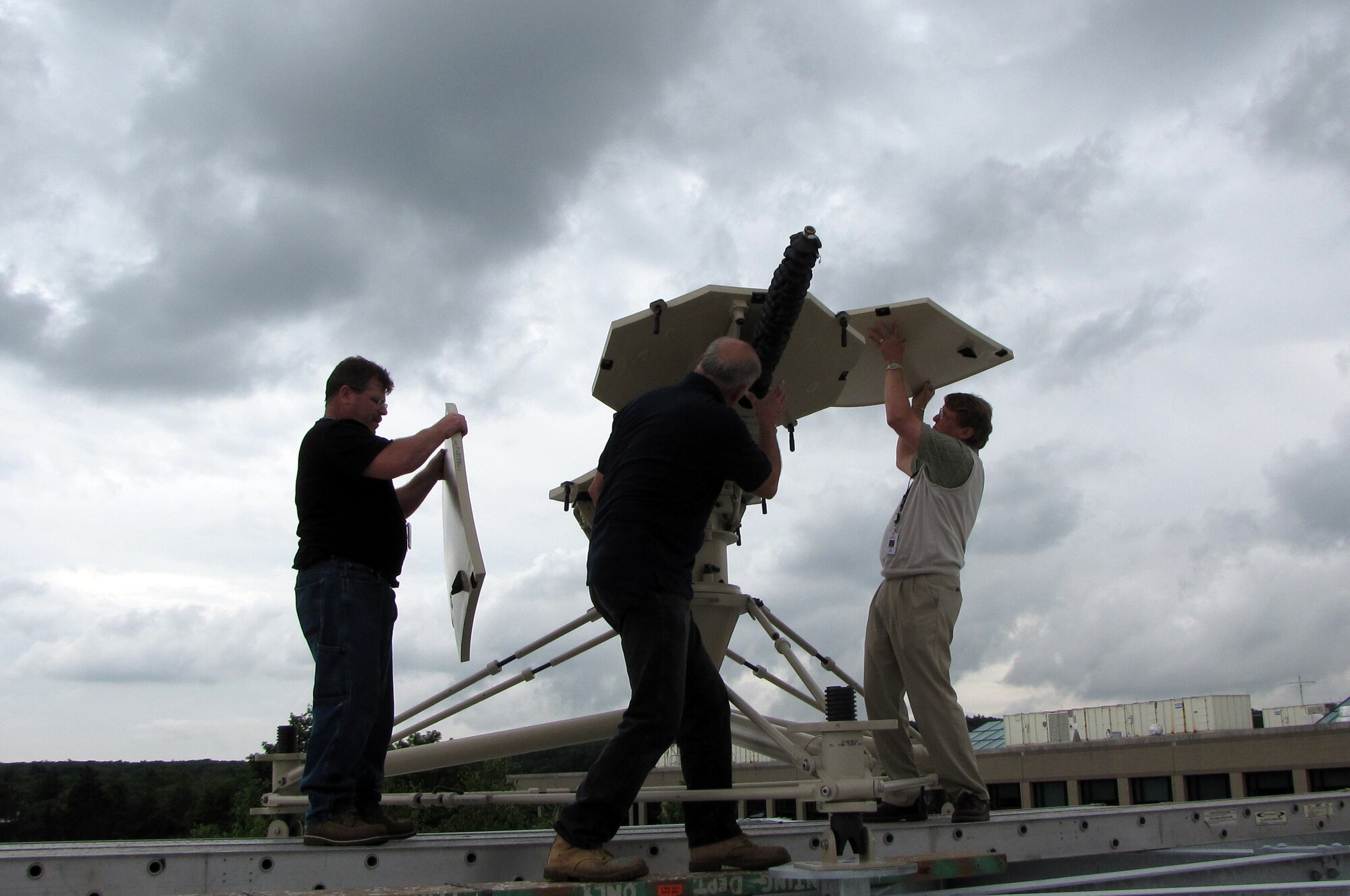 HANSCOM AIR FORCE BASE, Mass. – Members of a combined Electronic Systems Center-MITRE team assemble a Ground Multi-band Terminal antenna on the roof of a MITRE Bedford, Mass., campus building late last month.  Having a system available in the program office allows program officials to troubleshoot reported problems and review terminal changes and enhancements before they’re sent to the field.  (USAF Photo by Beth Farrington)