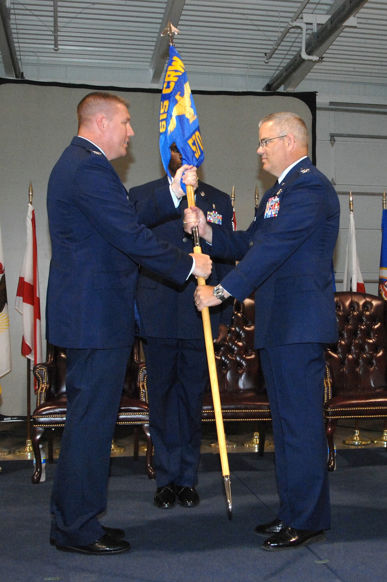 Col. John Lipinski, left, 615th Contingency Response Wing commander, hands the 570th Contingency Response Group guidon to Col. David Chandler during the 570th CRG change-of-command ceremony June 25. (U.S. Air Force photo/Nan Wylie)