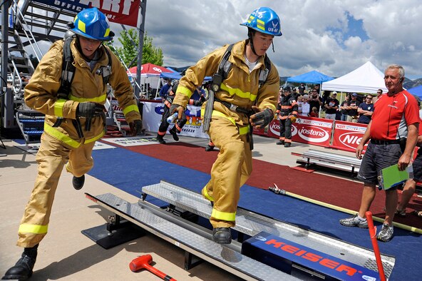 USAFA GIs relay team member Staff Sgt. Tanner Derosier, left, hands a baton to Airman 1st Class Steven Cimochoswki, who prepares to take on a Keiser Force Machine during a regional Firefighter Challenge at the U.S. Air Force Academy, Colo., June 26-27. The Keiser machine simulates forceable entry into a building. (U.S. Air Force photo/Mike Kaplan)
