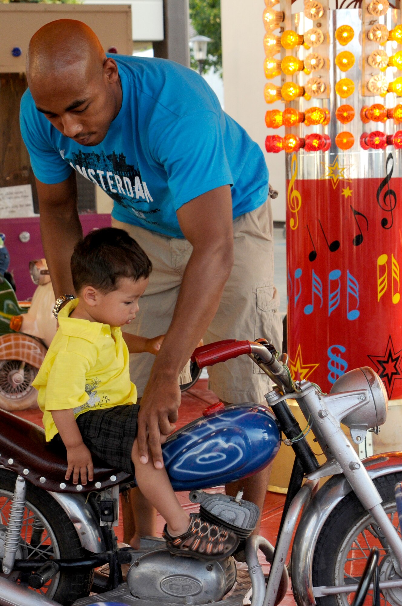 U.S. Air Force Staff Sgt. Chris Hucks (back), 1st Air and Space Communications Operations Squadron, adjusts his son, Chris Hucks Jr., 1, on a motorcycle ride, July 4, 2009, Kapaun Air Station, Germany. Kaiserslautern Military Community members celebrated the Rockin’ Fourth of July event with games, rides and concerts and ended the night with fireworks. (U.S. Air Force photo by Tech. Sgt. Kenneth 