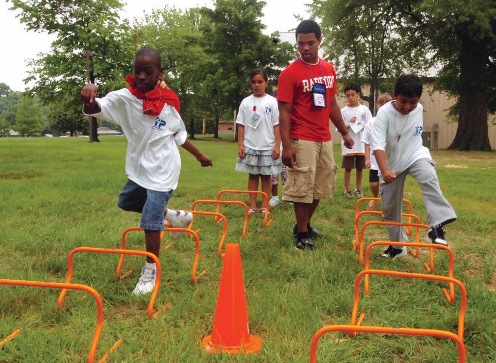 Elijah Murphy, 9, left, and Andrew Durham, 8, from the Youth Center, compete against time as they jump over mini hurdles as Rashad Brown, 18, son of Capt. Saudah Muhammad, 779th Aerospace Medicine Squadron nurse manager observes. The exercise was just one of six different circuit training stations provided by the Health and Wellness Center Friday. Elijah is the son of Petty Officer 1st Class Melenda Murphy, Naval District of Washington supply storekeeper, and Andrew is the son of Tech. Sgt. Lizu Hilton-Durham, 779th Medical Support Squadron NCO in charge of the customer service laboratory. (U.S. Air Force photo/ Bobby Jones)