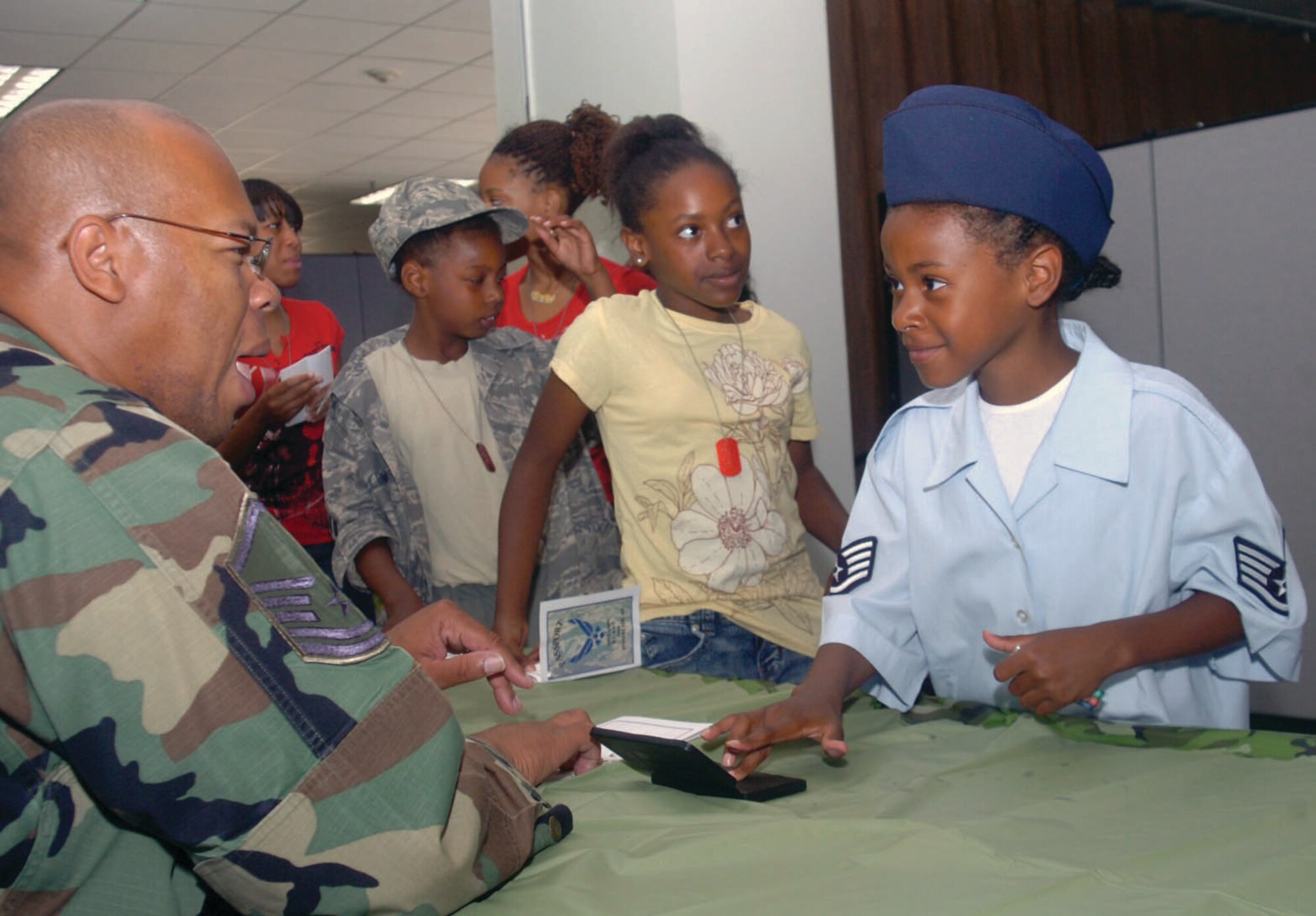 Master Sgt. Charles Mayes, 316th Security Forces Squadron NCO in charge of installation security, checks in “Staff Sgt.” Christierra Williams, 7, as she goes through the finger printing processing line for her “passport.” Christierra is the daughter of Staff Sgt. Shantay Williams, Headquarters, Air Force Office of Special Investigations. More than 180 children participated in Operation Kids Understanding Deployment Operations Friday at the Child Development Center. The purpose of Operation K.U.D.O.S. is to familiarize the children with what their friends and family go through prior to deployment operations. The event was sponsored by the 316th Logistics Readiness Squadron. (U.S. Air Force photo/ Bobby Jones)