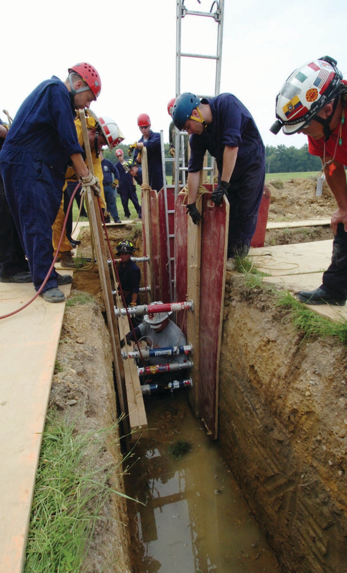 Senior Airman Matthew Silliman, left, and Senior Airman Timothy Mulvaney, right, both 316th Civil Engineer Squadron firefighters, observe as trench rescue braces are put into place to support the walls from collapsing inside a 10-foot trench during a trench rescue exercise on the East Side of base Friday. The course was just one of various life saving training courses at Andrews provided by the Maryland Fire Rescue Institute. Other courses that are scheduled during 45 days  of rescue training include confined-space rescue, high and low angle rescue, vehicle machinery rescue and swift water rescue. (U.S. Air Force photo/ Bobby Jones)