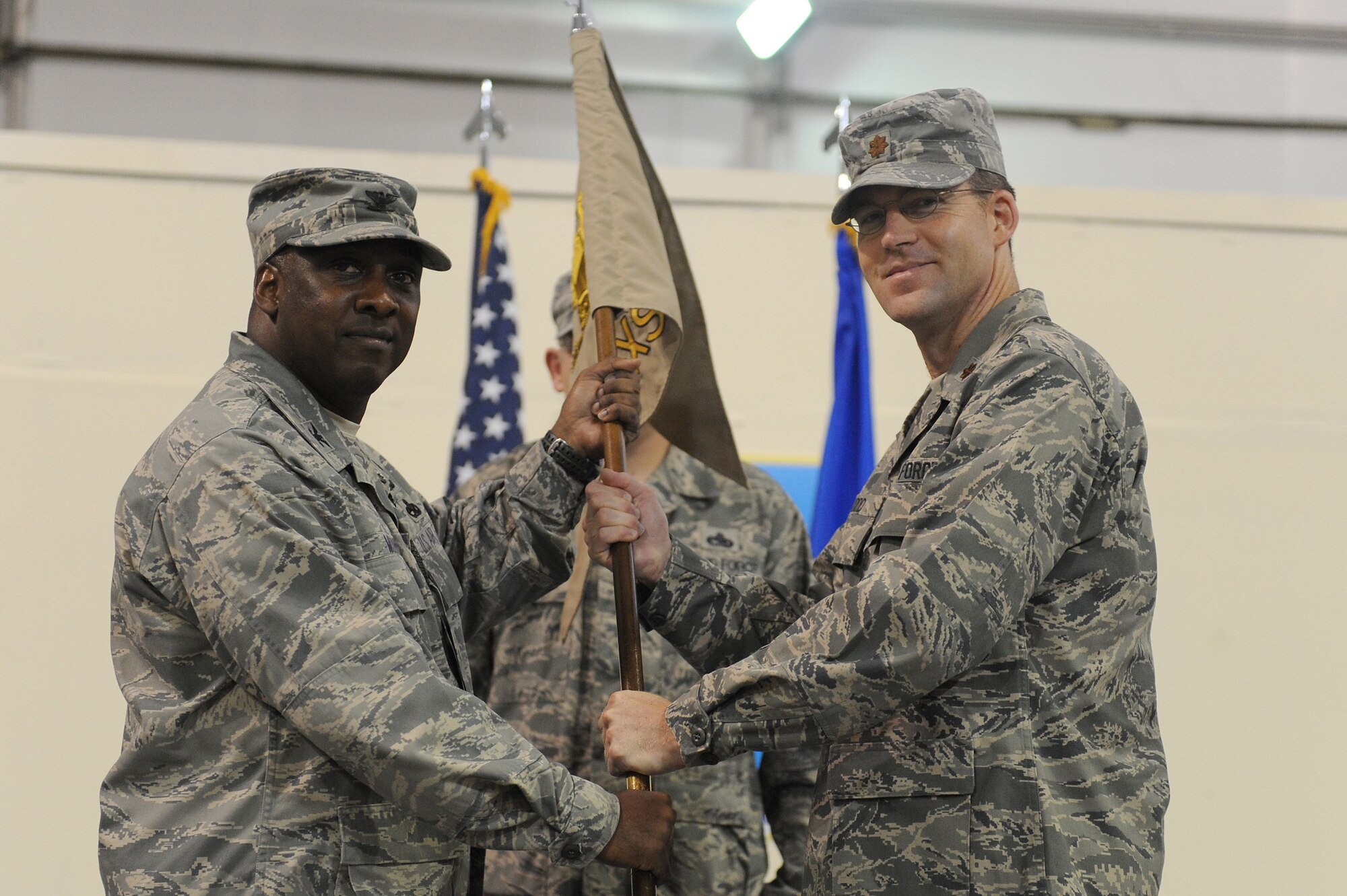 SOUTHWEST ASIA - Col. Ricky Murphy, 380th Expeditionary Maintenance Group, commander, passes the guidon of the 380th Expeditionary Maintenance Squadron to Maj. James Hood as he takes command, July 4 at an undisclosed location in Southwest Asia. Major Hood comes from Maxwell AFB, Ala. joining the 380th Air Expeditionary Wing to lead the 380th EMXS. (U.S. Air Force photo by Senior Airman Brian J. Ellis)