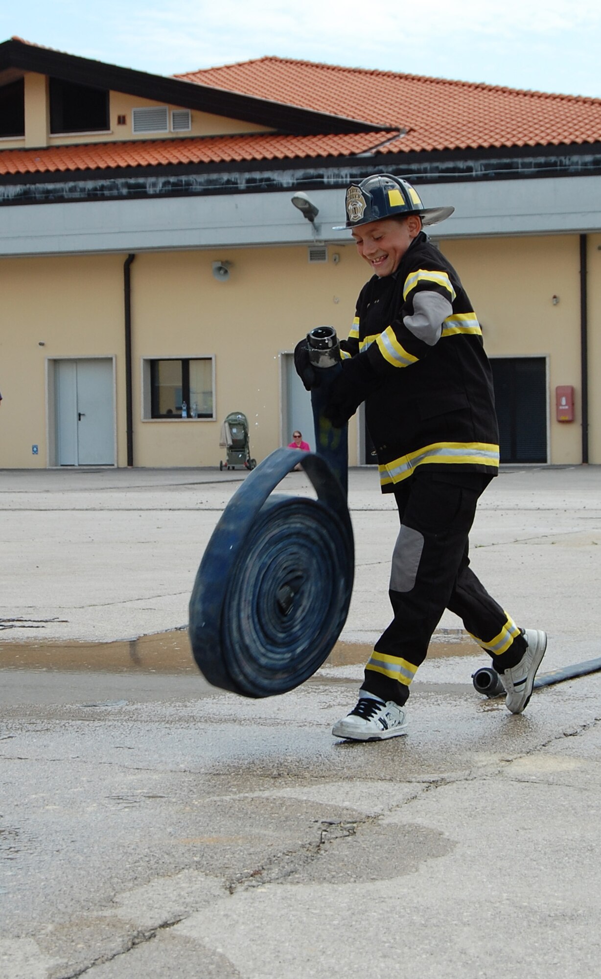 Green Team member Gregory Nicodemus rolls out a fire hose as part of the Aviano Fire Camp relay competition July 3, 2009 at the base fire station. The week-long camp, which was open to 10-13-year-old children, taught attendees basic firefighter knowledge and skills. (U.S. Air Force photo/Staff Sgt. Lindsey Maurice)