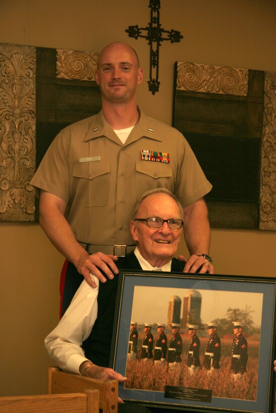 Capt. Gary Cox, executive officer for Recruiting Station Kansas City, poses with former Marine Robert Sander who displays his gift from the Marines of Recruiting Station Kansas City July 7. Sander, who turned 90-years-old on July 4, continues to serve his community through volunteering at the St. Joseph Medical Center in Overland Park, Kan.