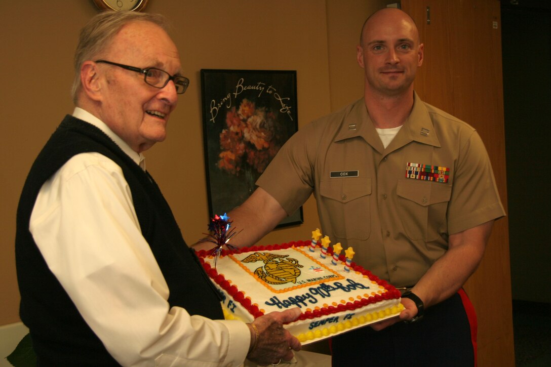 OVERLAND PARK, Kan. - Former Marine Robert Sander stands with Capt. Gary Cox, executive officer for Recruiting Station Kansas City and displays his birthday cake from local Marines July 7. Sander is a 90-year-old Marine Corps veteran who continues to serve his community through volunteering at the St. Joseph Medical Center, Overland Park, Kan. RS Kansas City gave the cake in celebration of Sander's 90th birthday and in gratitude for his service.