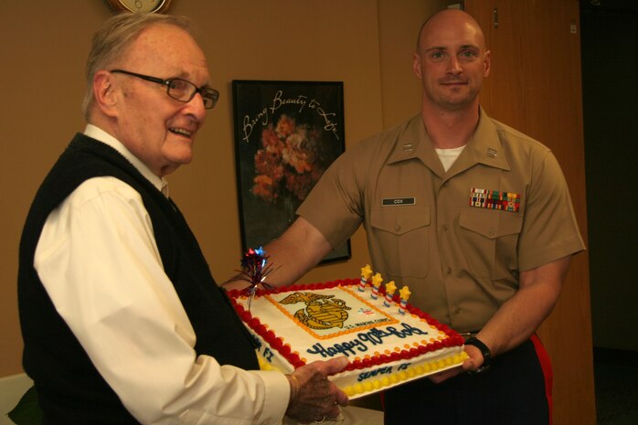 OVERLAND PARK, Kan. - Former Marine Robert Sander stands with Capt. Gary Cox, executive officer for Recruiting Station Kansas City and displays his birthday cake from local Marines July 7. Sander is a 90-year-old Marine Corps veteran who continues to serve his community through volunteering at the St. Joseph Medical Center, Overland Park, Kan. RS Kansas City gave the cake in celebration of Sander's 90th birthday and in gratitude for his service.